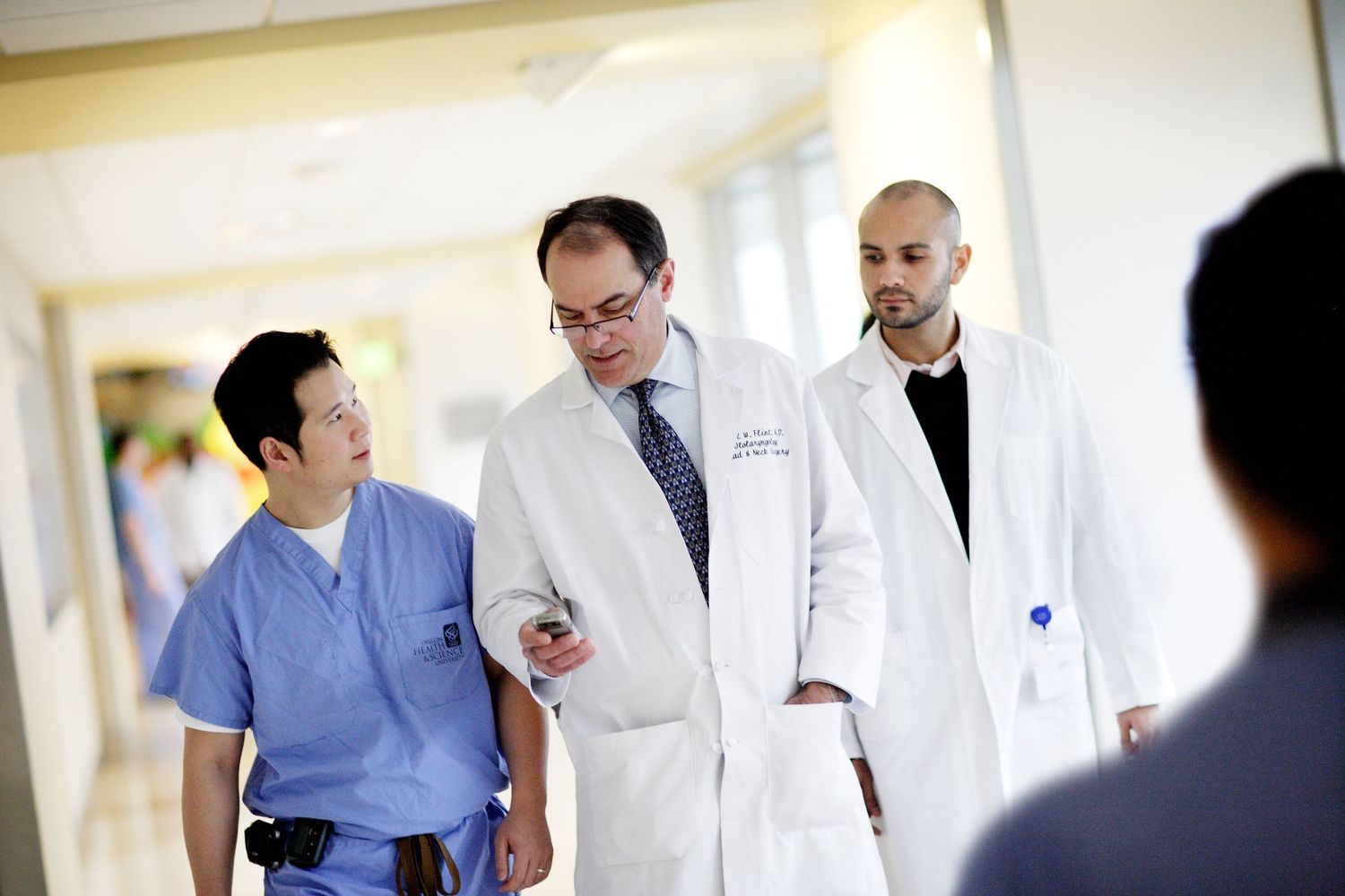 Medical team discussing patient case while walking through hospital corridor.