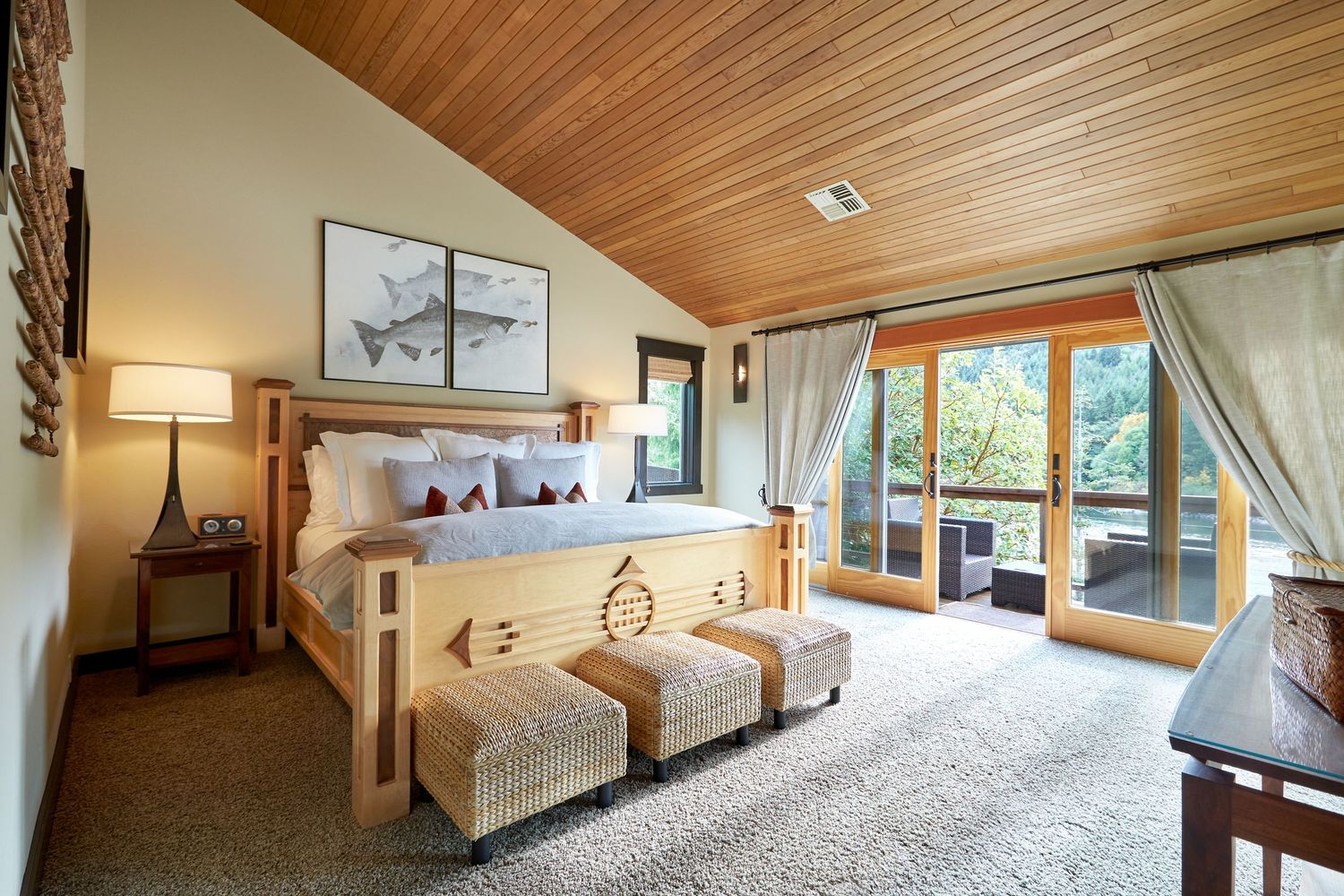 Luxurious bedroom with wood-paneled ceiling, white bedding, and large windows offering forest views.
