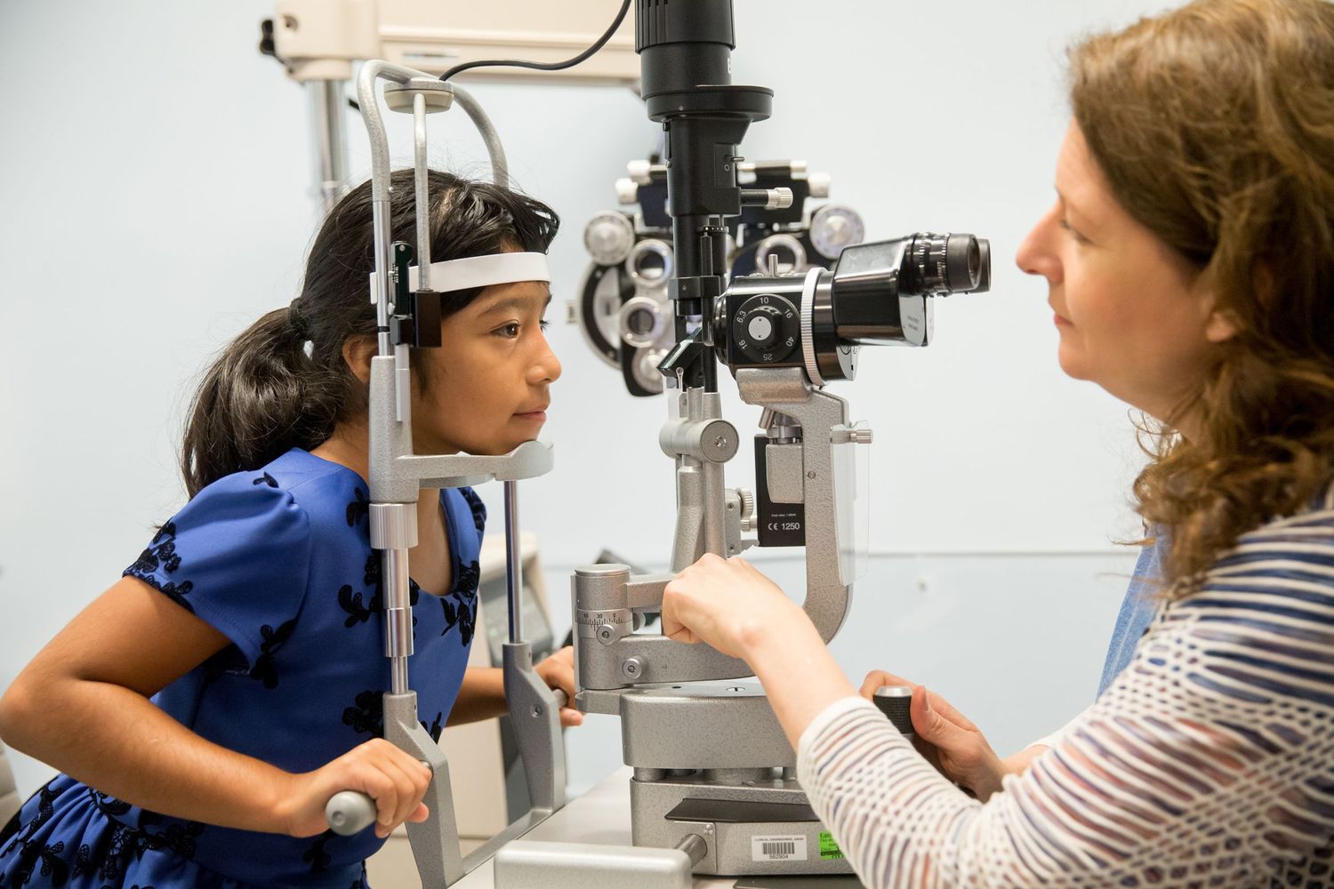 Patient receiving eye examination with specialized optometry equipment.