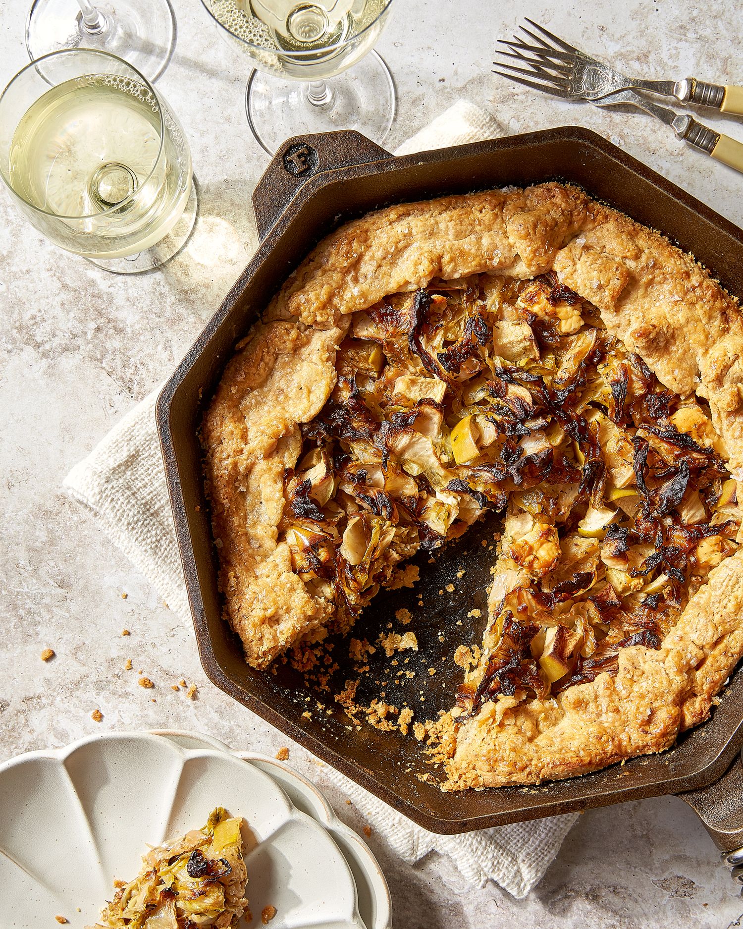 Rustic fruit galette with nuts in cast iron skillet served with white wine.