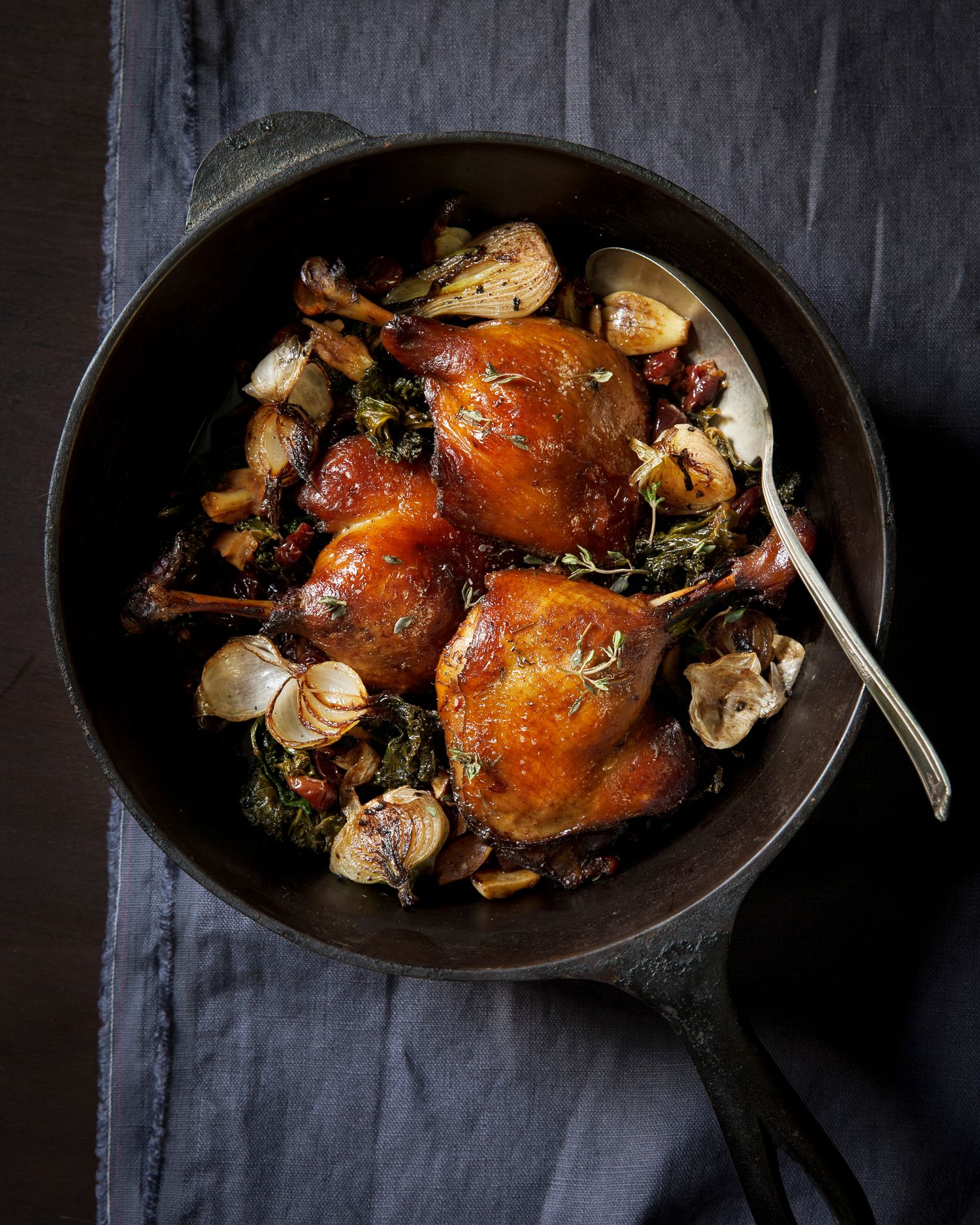 Roasted chicken with herbs and vegetables in dark cast iron pan.