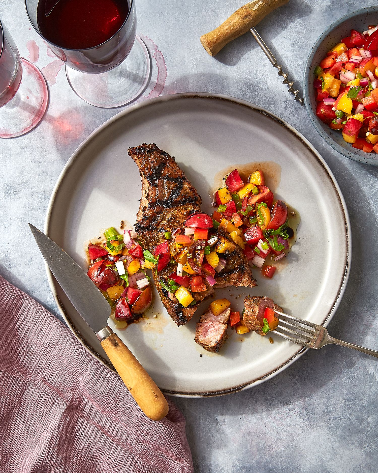 Grilled steak with colorful bell pepper salsa served on white plates.