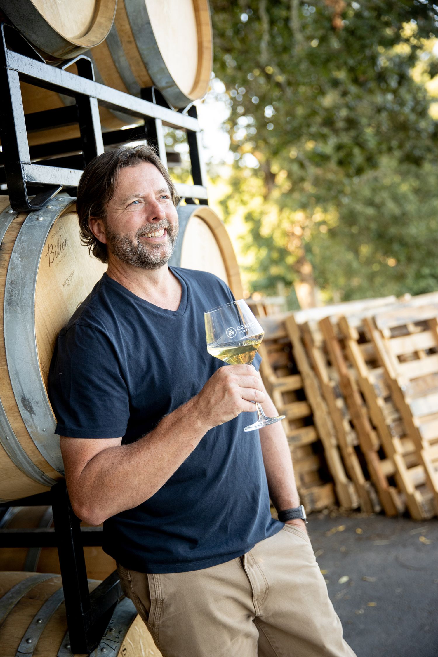Wine tasting experience near oak barrels in a rustic outdoor setting.
