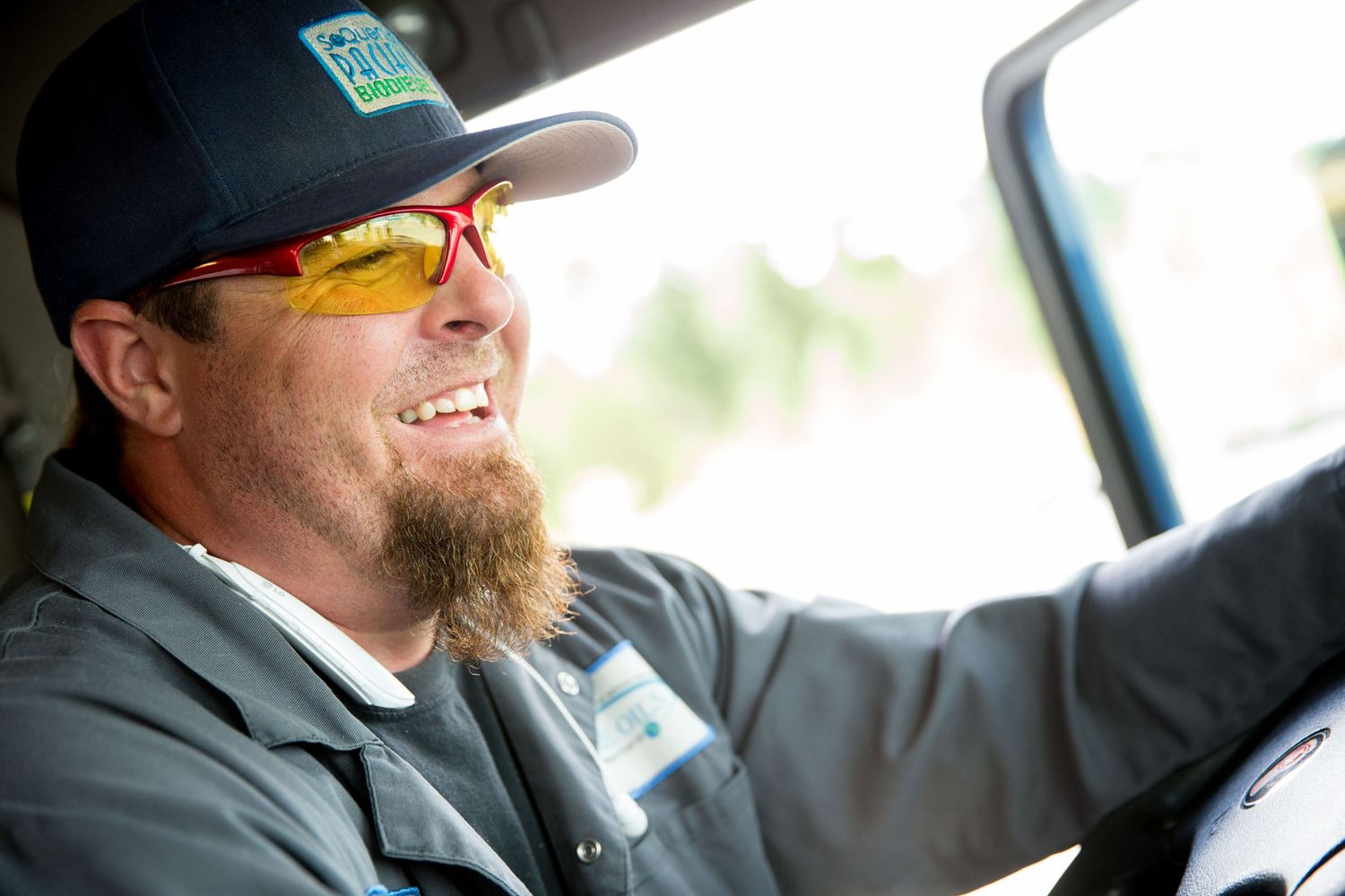 Professional driver in safety glasses and cap operates vehicle.