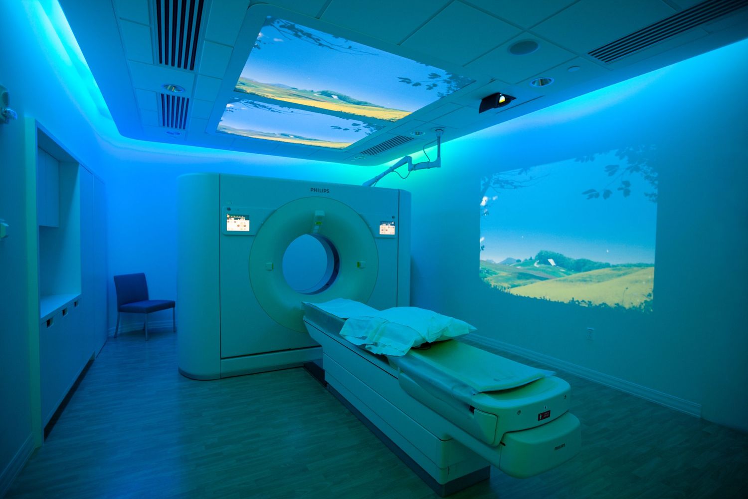 Modern medical imaging room with blue ambient lighting and projection screens.