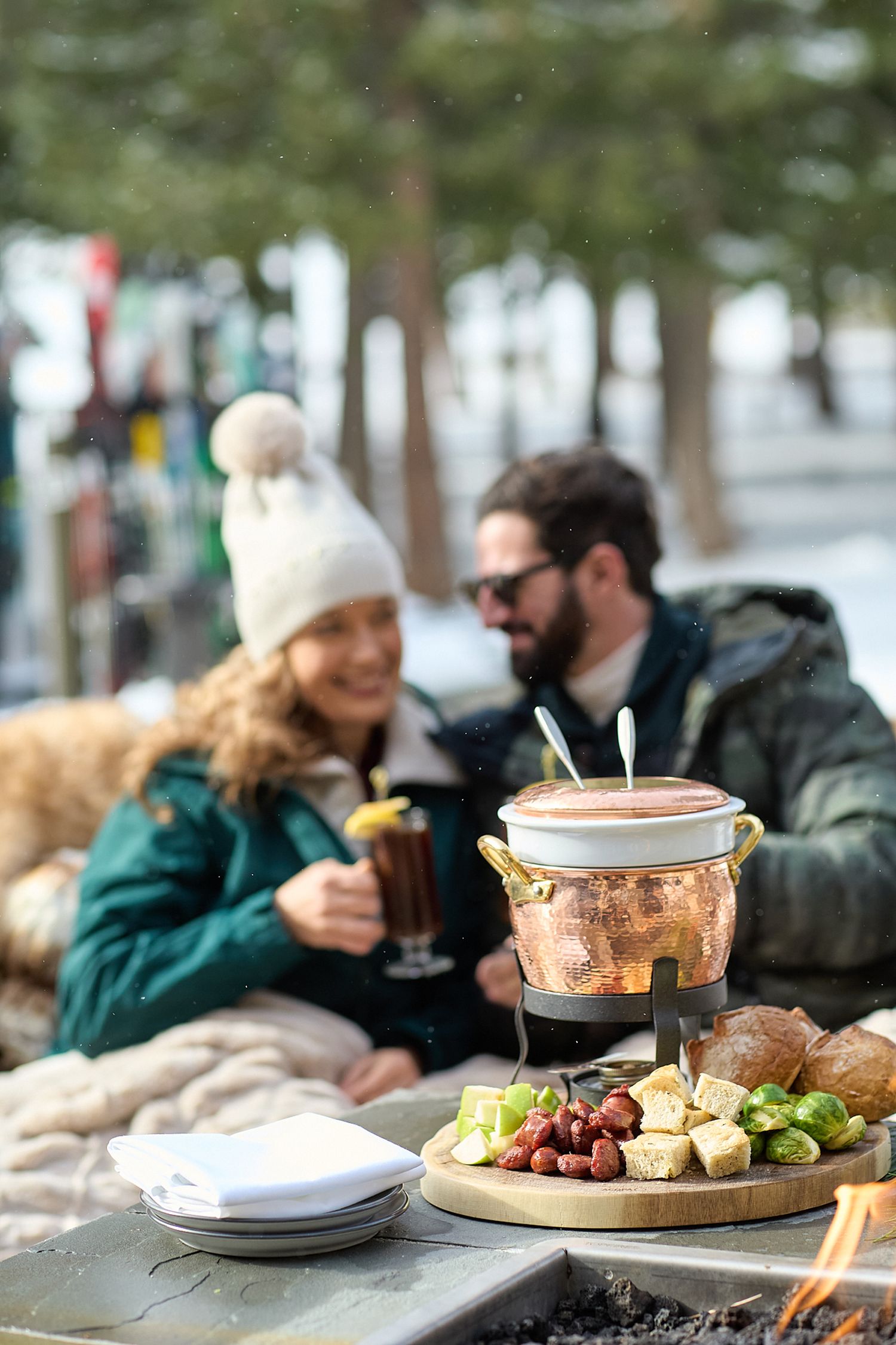 Outdoor dining scene with plates and copper cookware on a rustic wooden table.