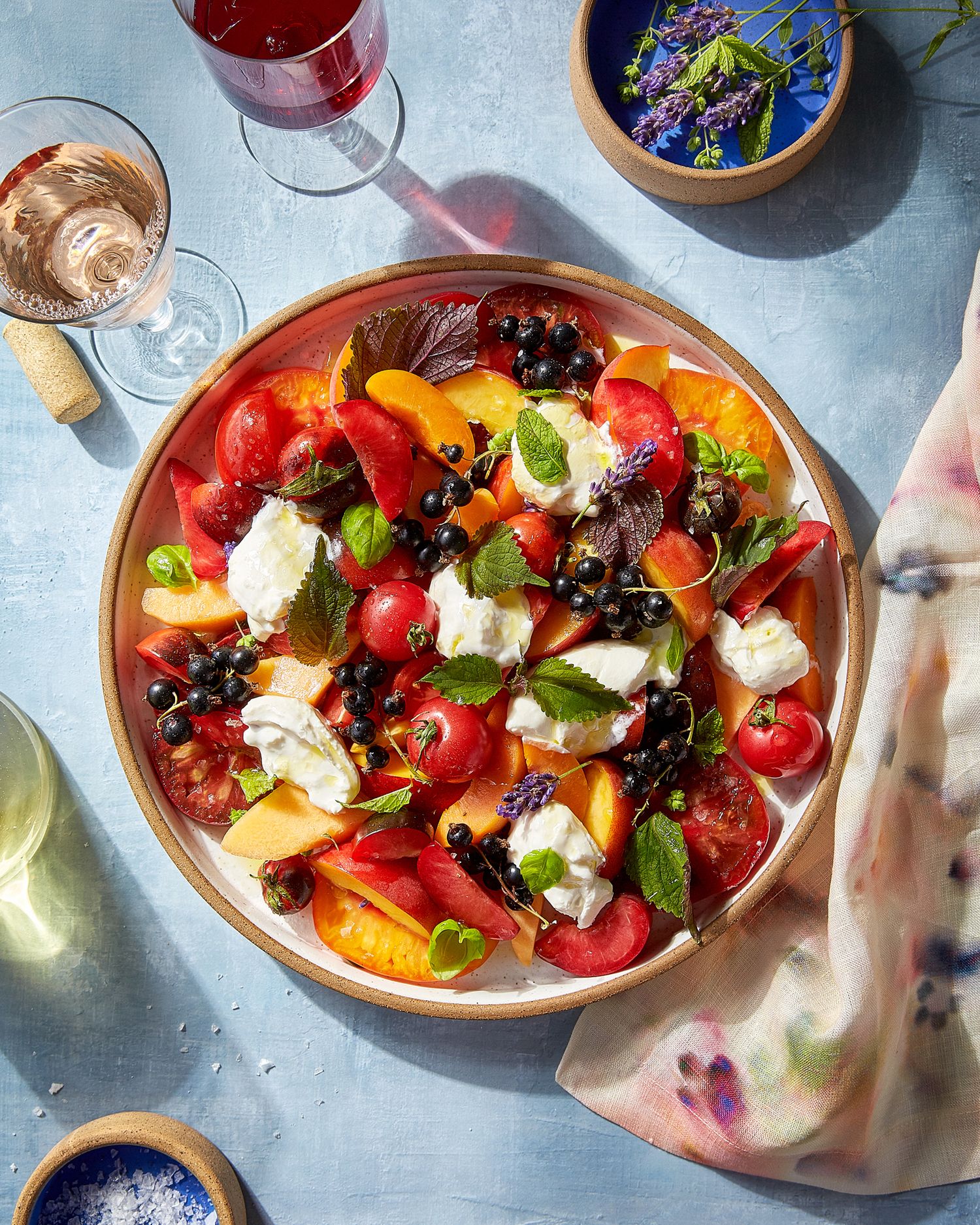 Fresh fruit and cheese platter with colorful berries, citrus, and soft cheese garnished with herbs.