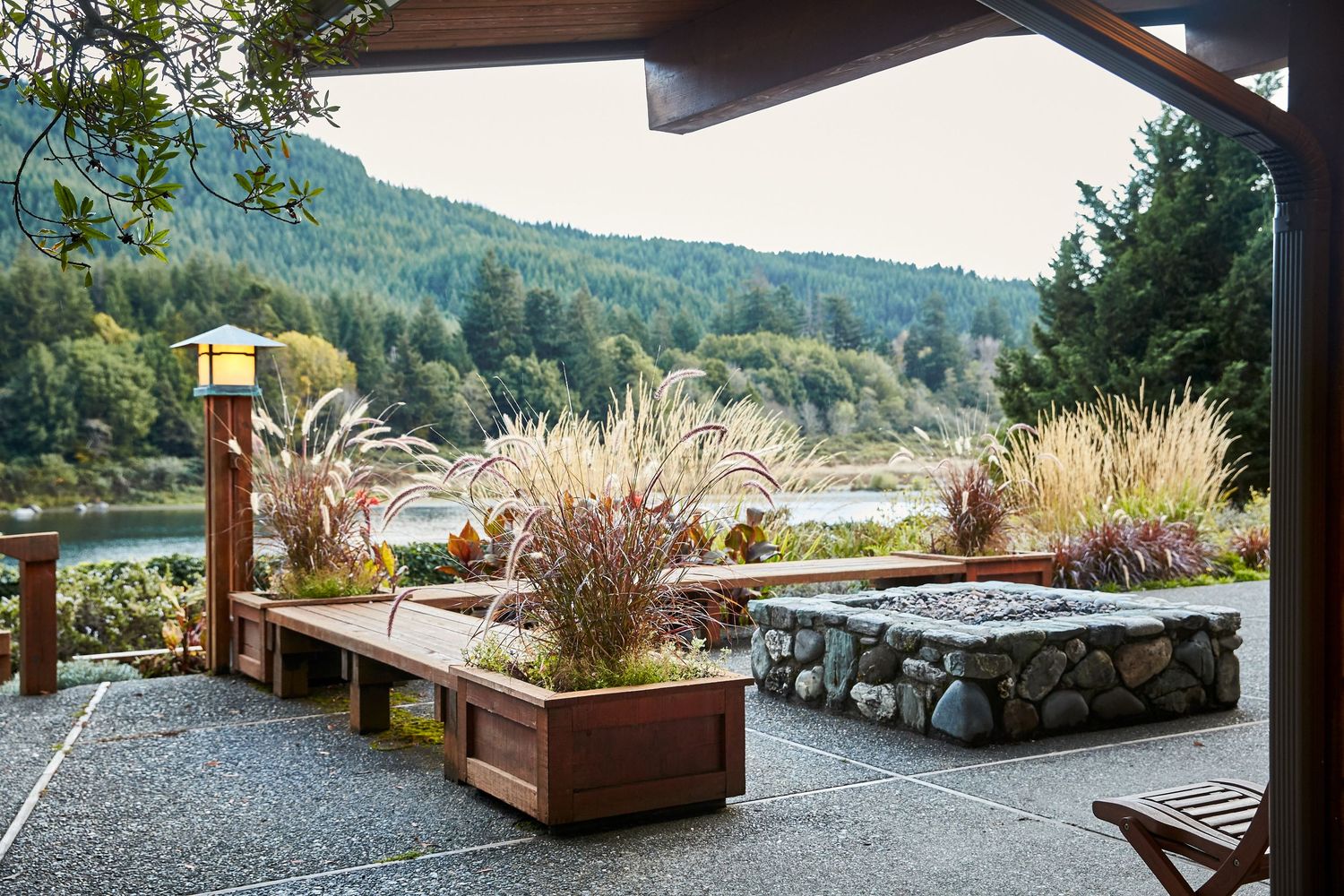 Modern outdoor patio with stone walls and planters overlooking a scenic mountain landscape.