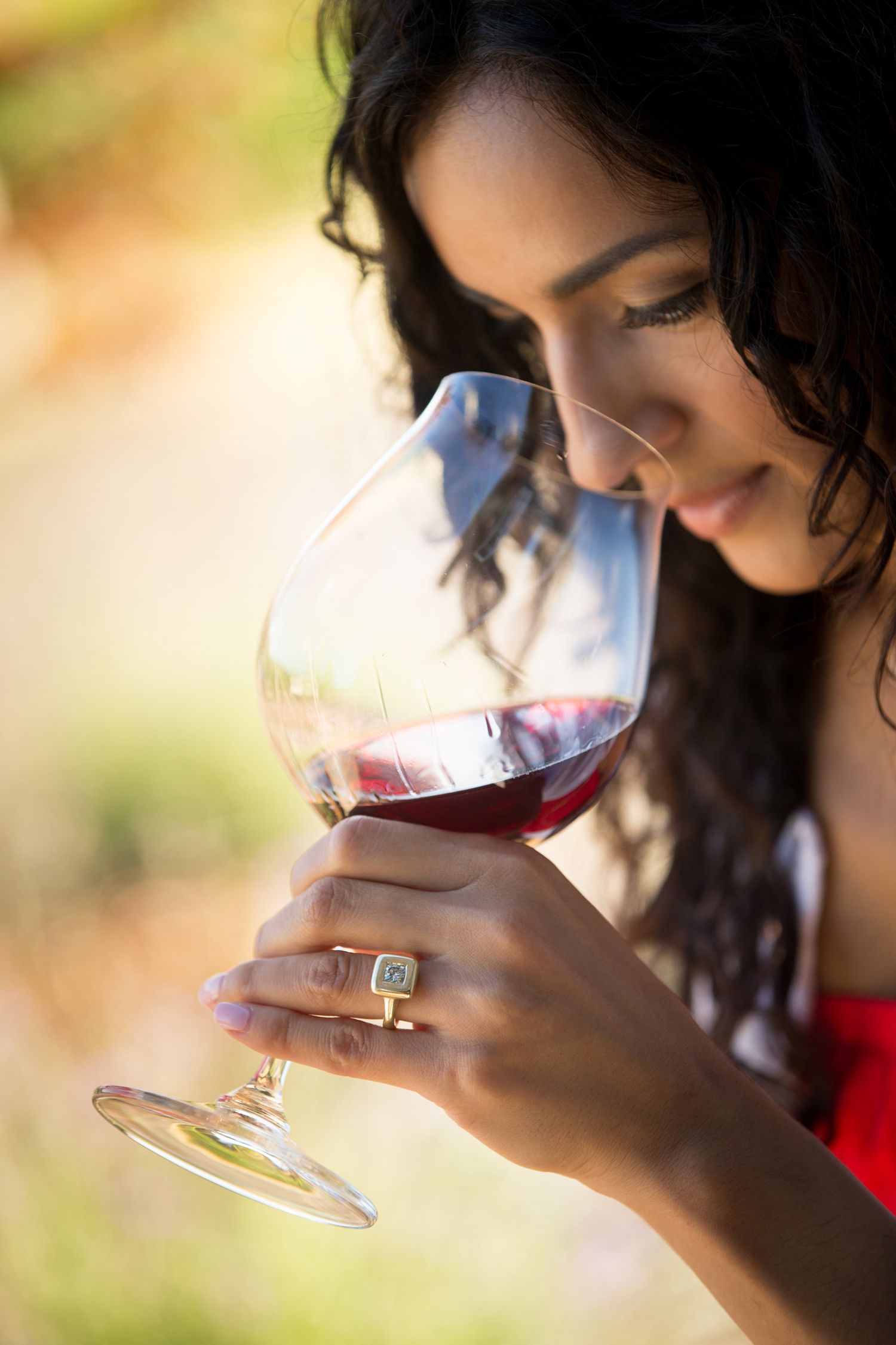 Wine glass held against natural light to examine the wine's color and characteristics.