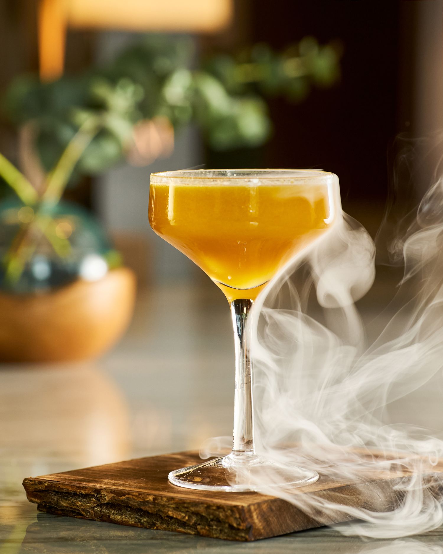 Smoky craft cocktail in stemmed glass with dramatic vapor effect.