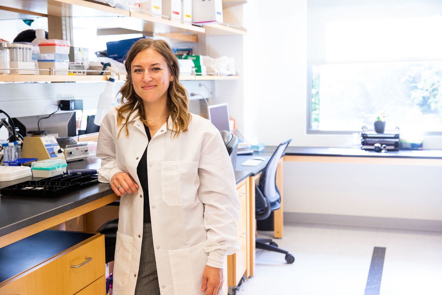 Laboratory technician in white coat working with scientific equipment in modern research facility.