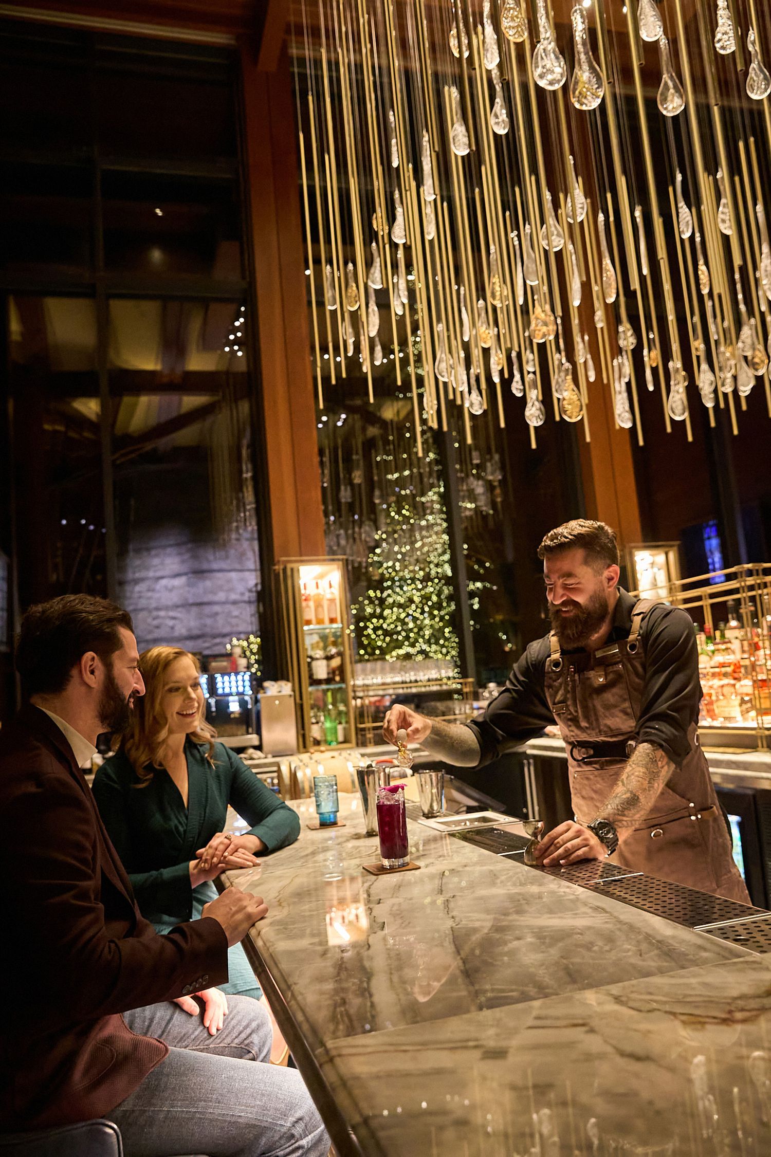 Friends enjoying dinner conversation under elegant crystal pendant lighting at an upscale restaurant.
