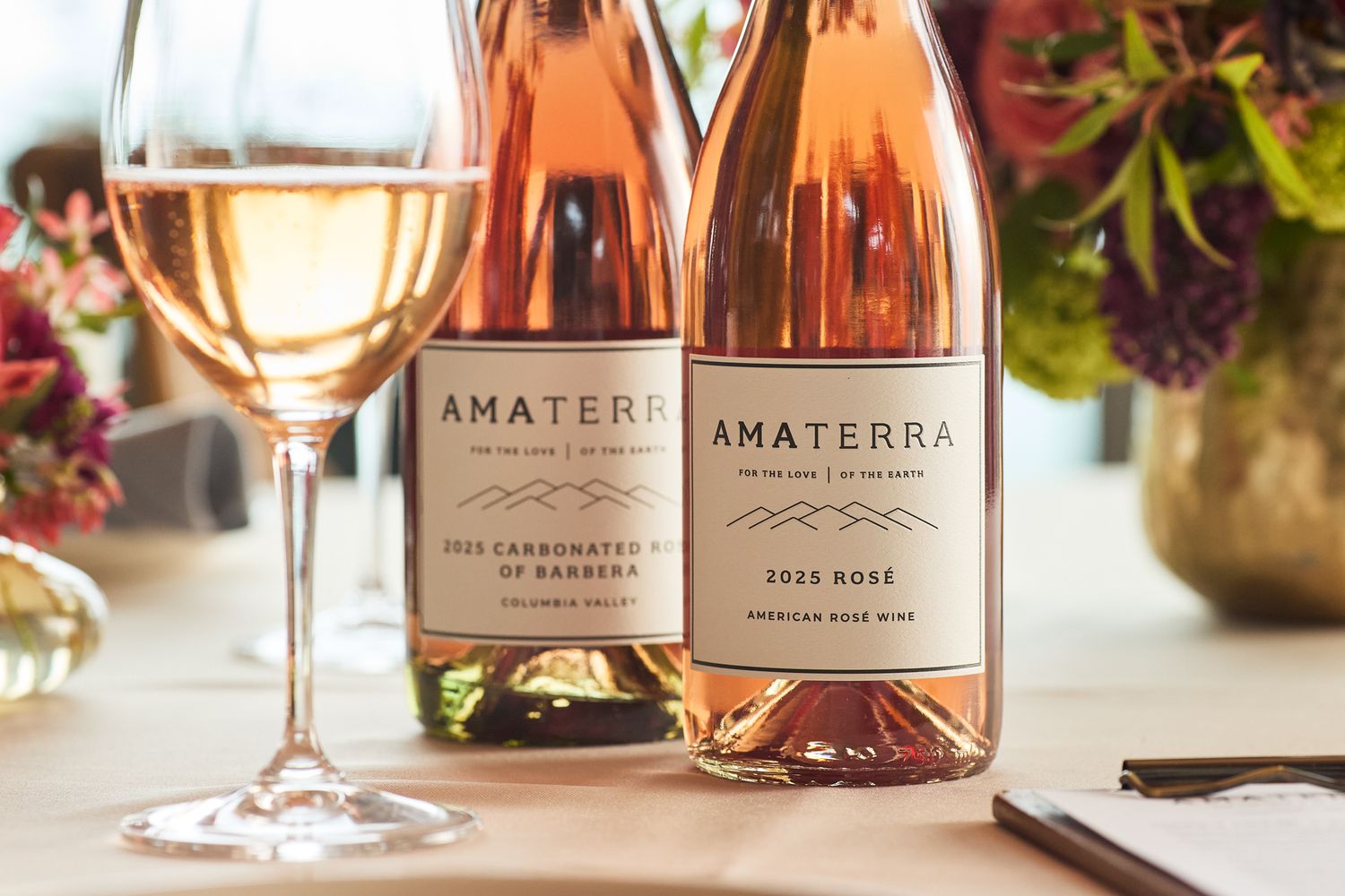 Amaterra winery rosé wine bottles and glass on a table, featuring 2022 Carbonated Rosé and 2021 Rosé.