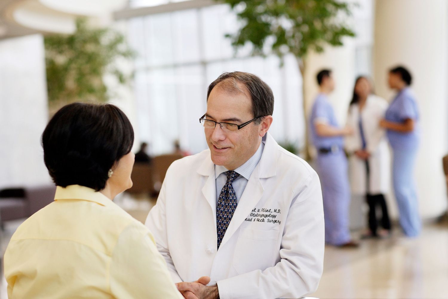 Medical staff interacting with patients in bright modern hospital hallway.