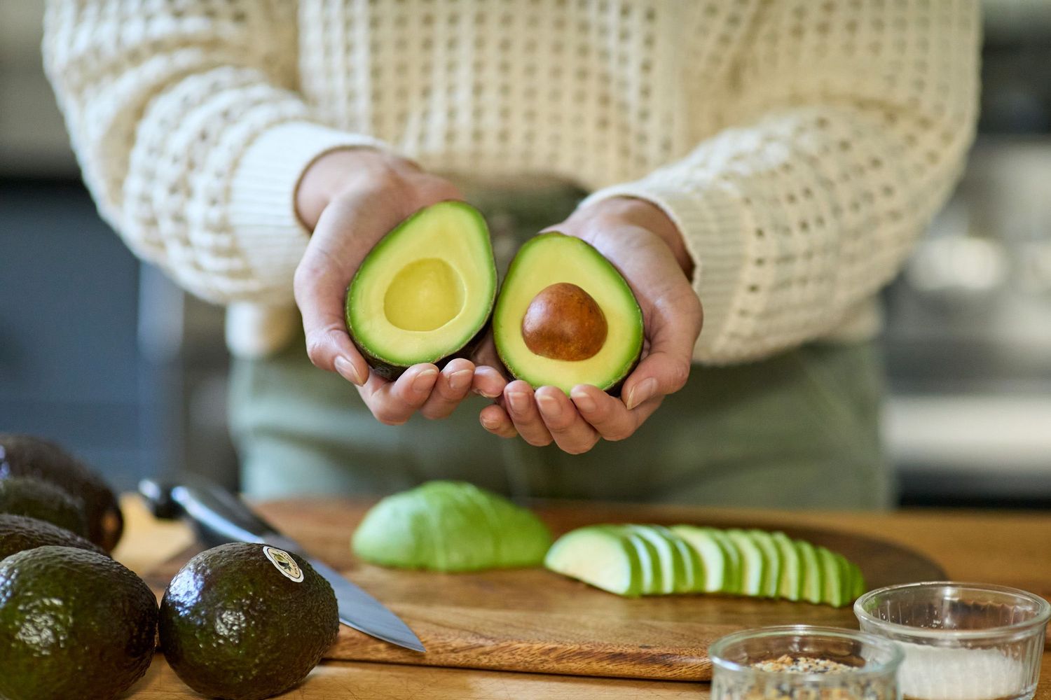 A series of hands preparing avocados and fresh ingredients in a kitchen setting.