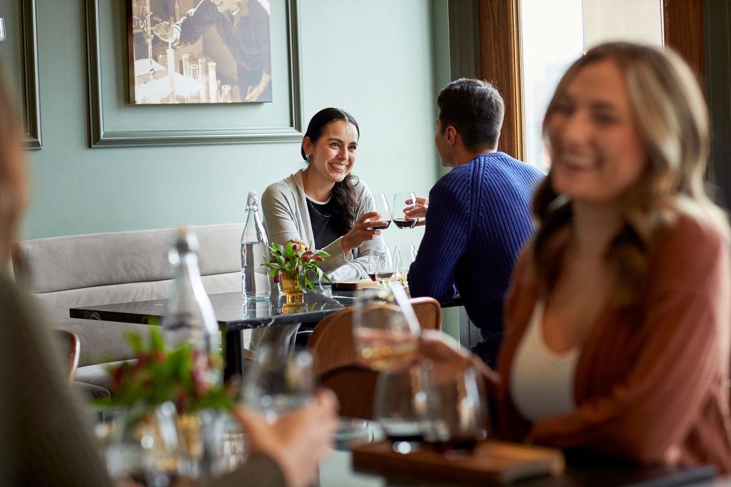Diners enjoying a meal and drinks at a casual restaurant with mint green walls.