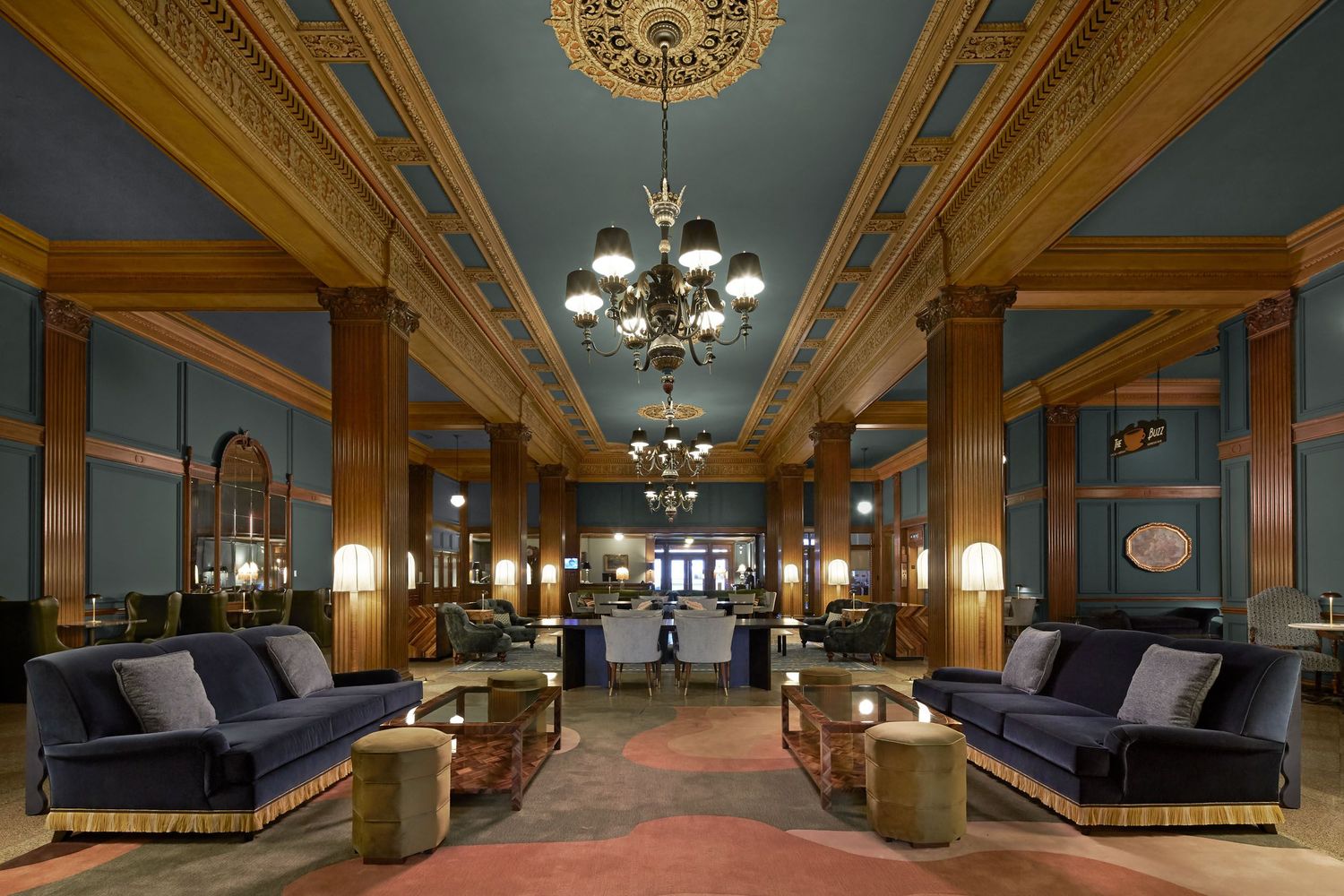 Elegant hotel lobby interior with ornate wooden beams, chandeliers, and luxurious seating areas.