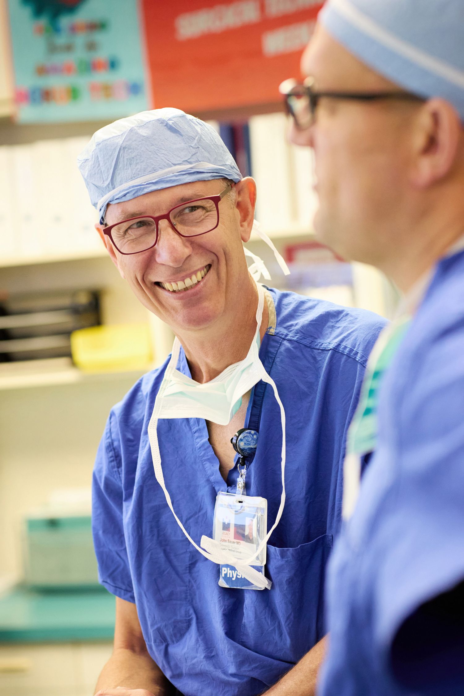Healthcare professionals in blue scrubs discussing in hospital corridor.