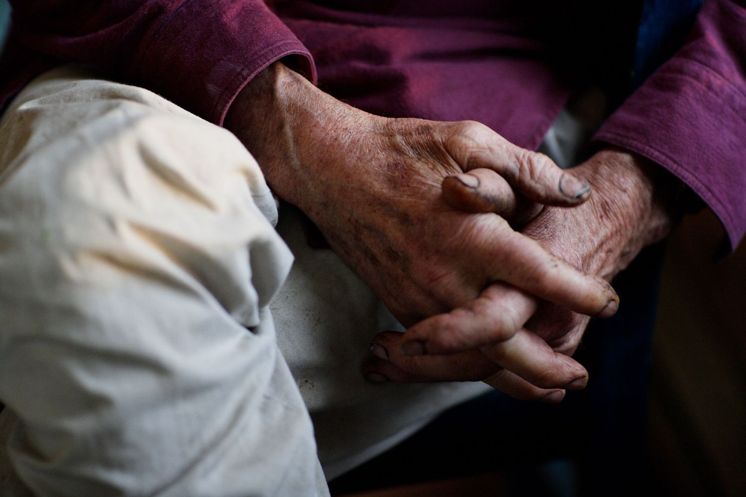 Weathered hands shown in close-up detail against a dark background.
