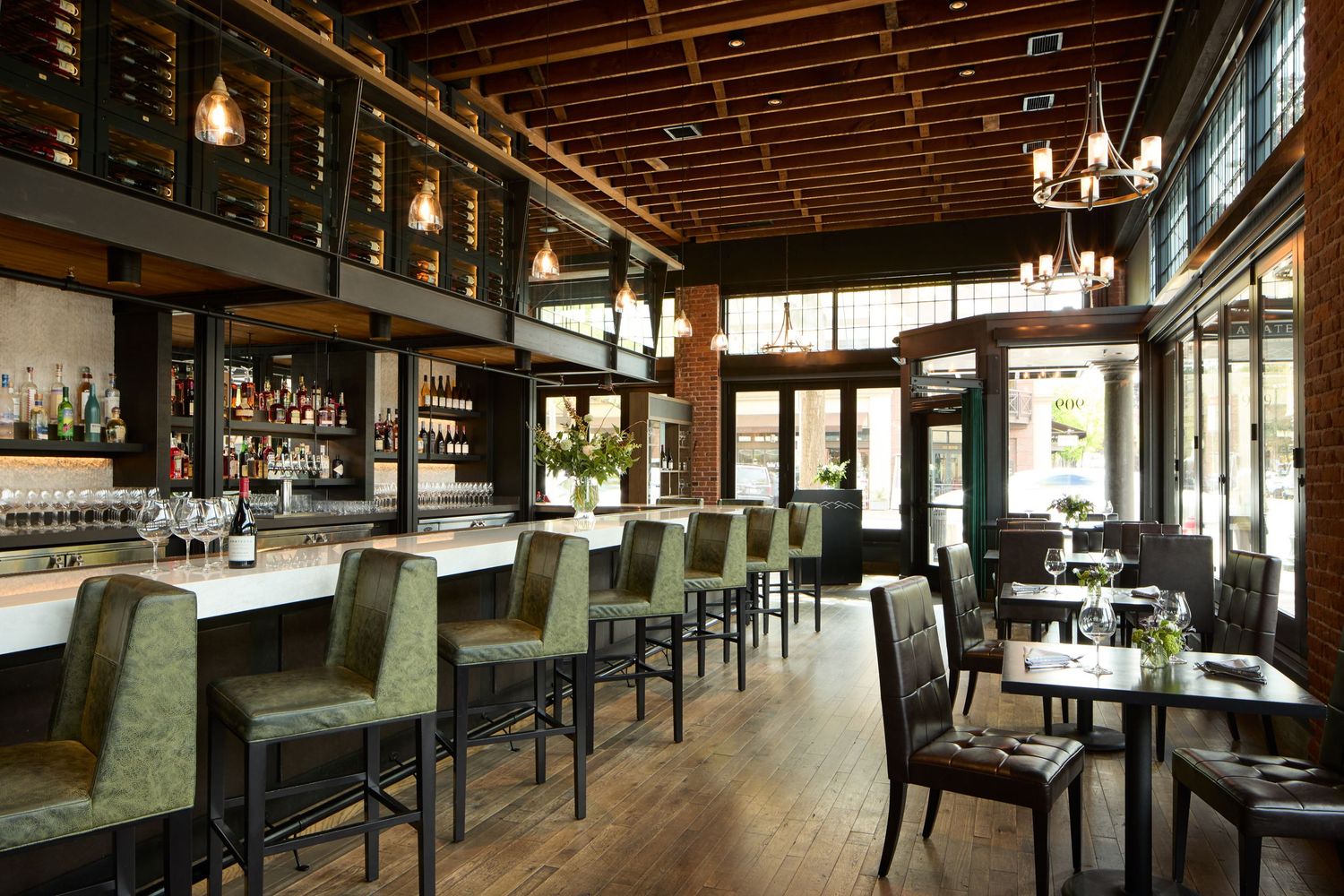 Elegant restaurant interior with dark wood tables, exposed brick walls, and warm lighting creating an upscale dining atmosphere.