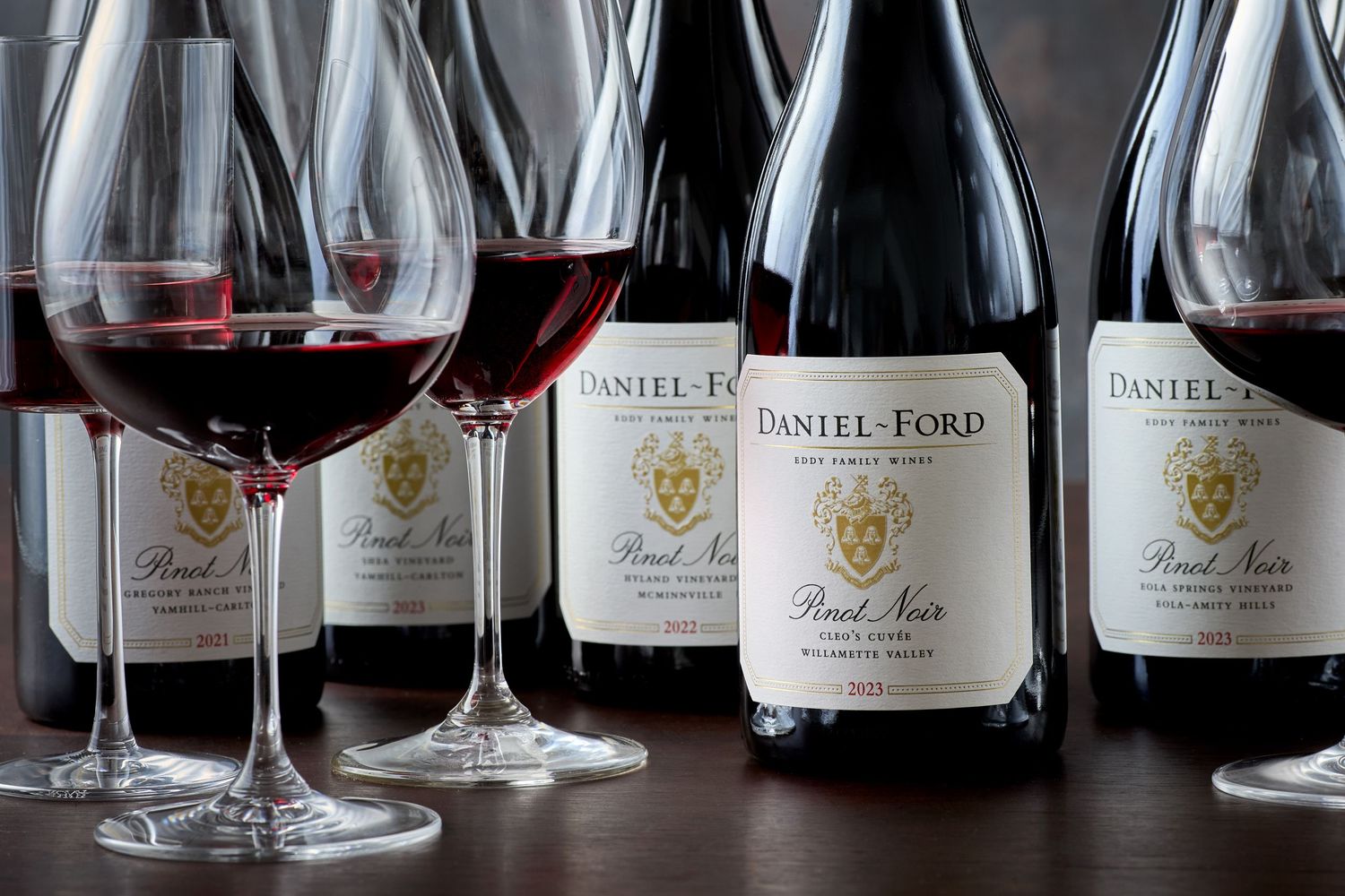 Several glasses and bottles of Daniel Ford wine arranged on a dark surface.