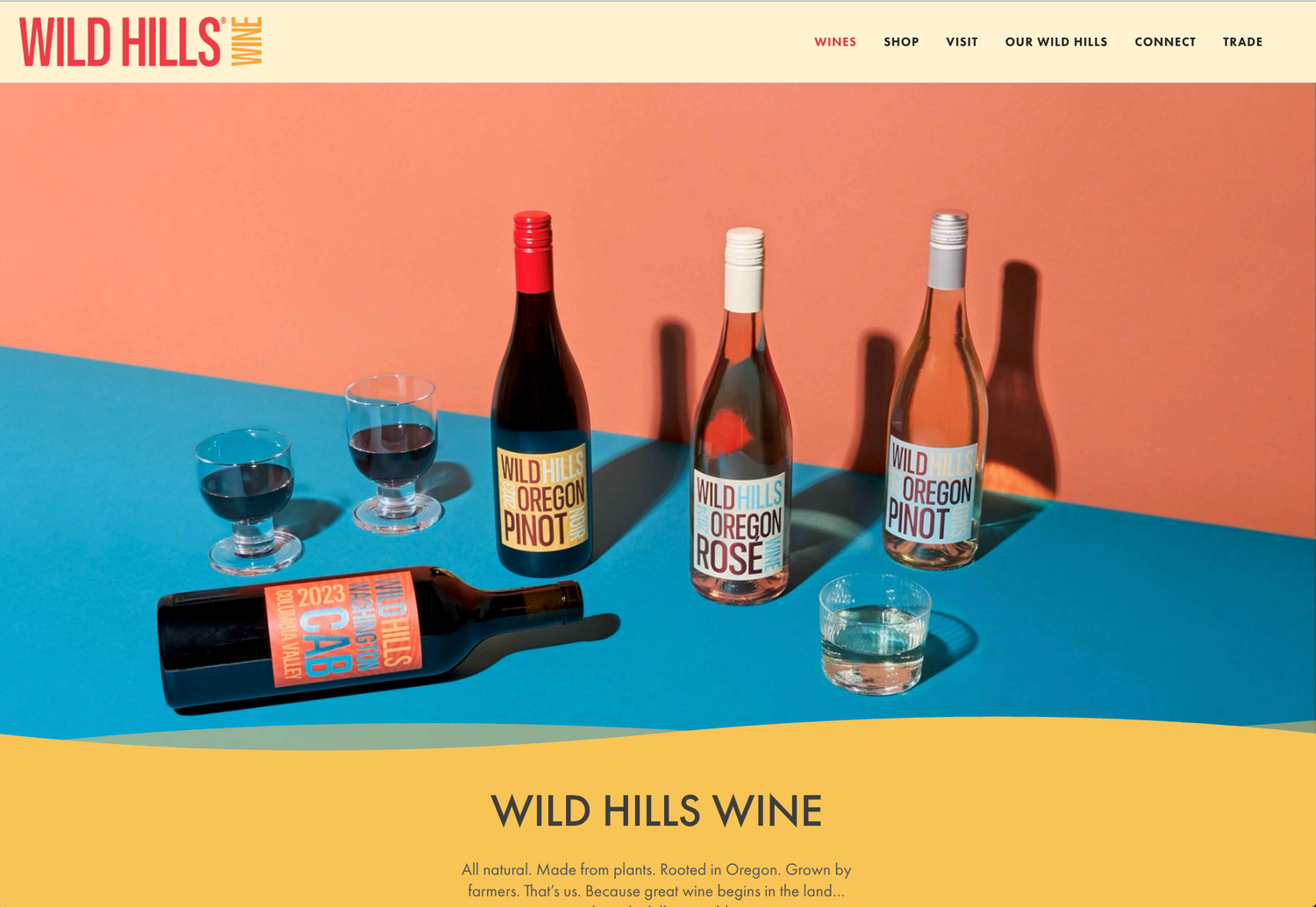 Wild Hills Wine website homepage showing bottles of Oregon Pinot Noir and Rosé with wine glasses against a bold coral and blue backdrop.