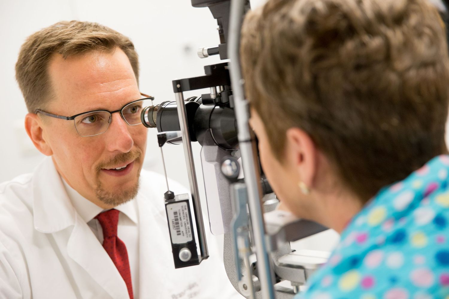 Eye examination being conducted with specialized optometry equipment in medical office.
