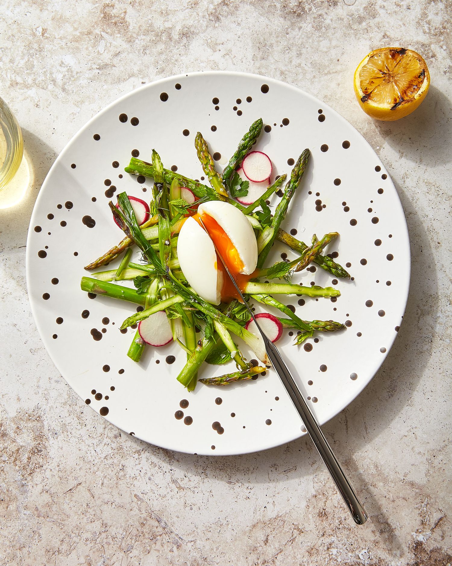 Elegant plated salad with asparagus and radishes on dotted white plates.