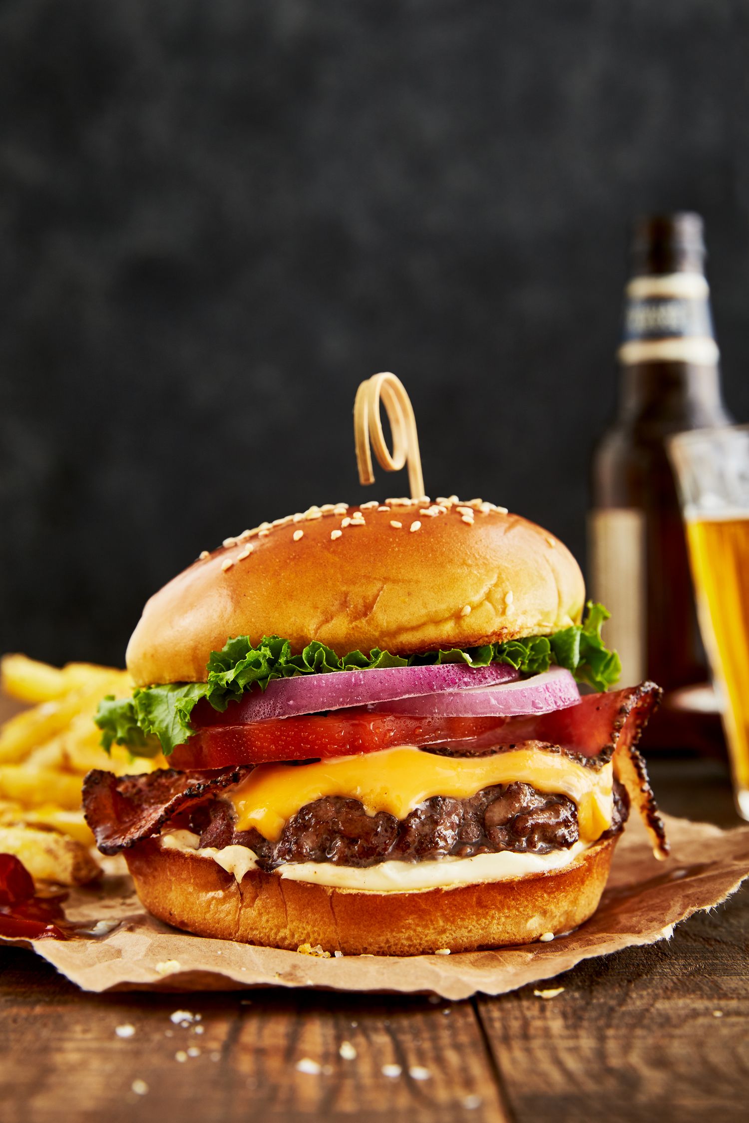 Classic cheeseburgers with melted cheese and fresh vegetables on rustic wooden surface.