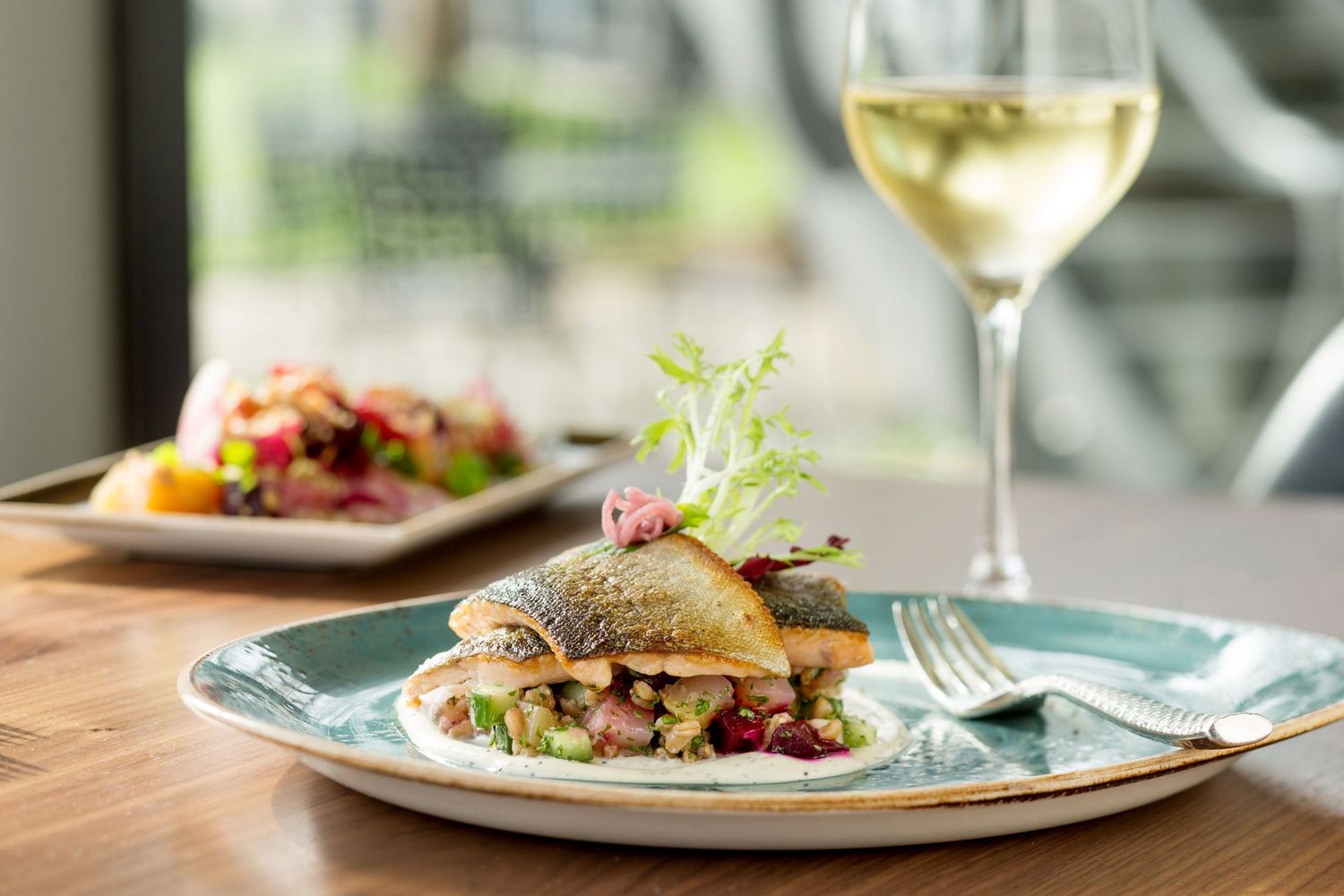 Fine dining table setting with wine glass and elegantly plated appetizers.