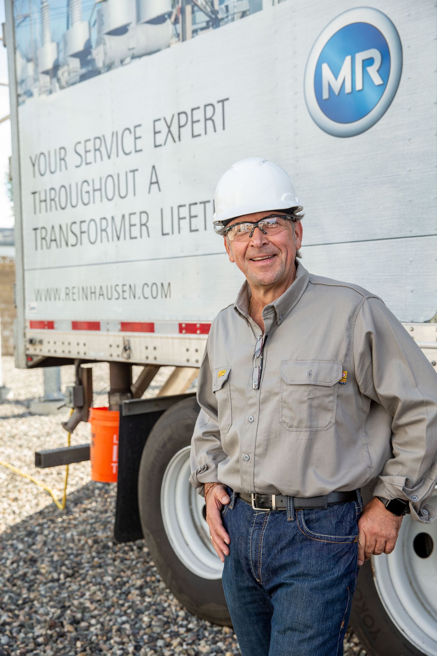 Industrial service worker in hard hat standing next to maintenance vehicle.