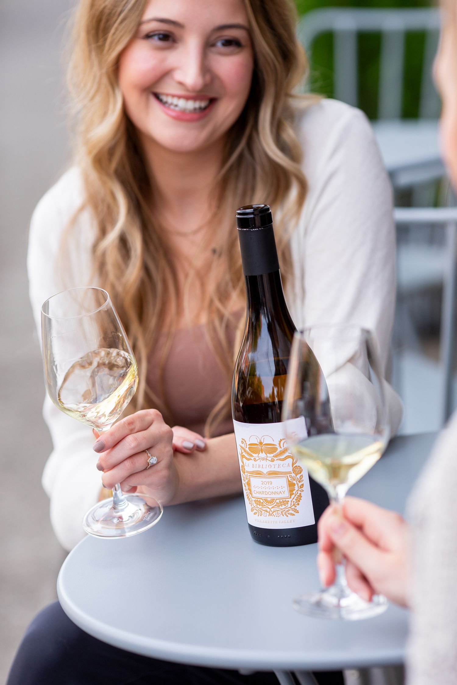 White wine tasting experience with bottle and glasses on outdoor patio table.