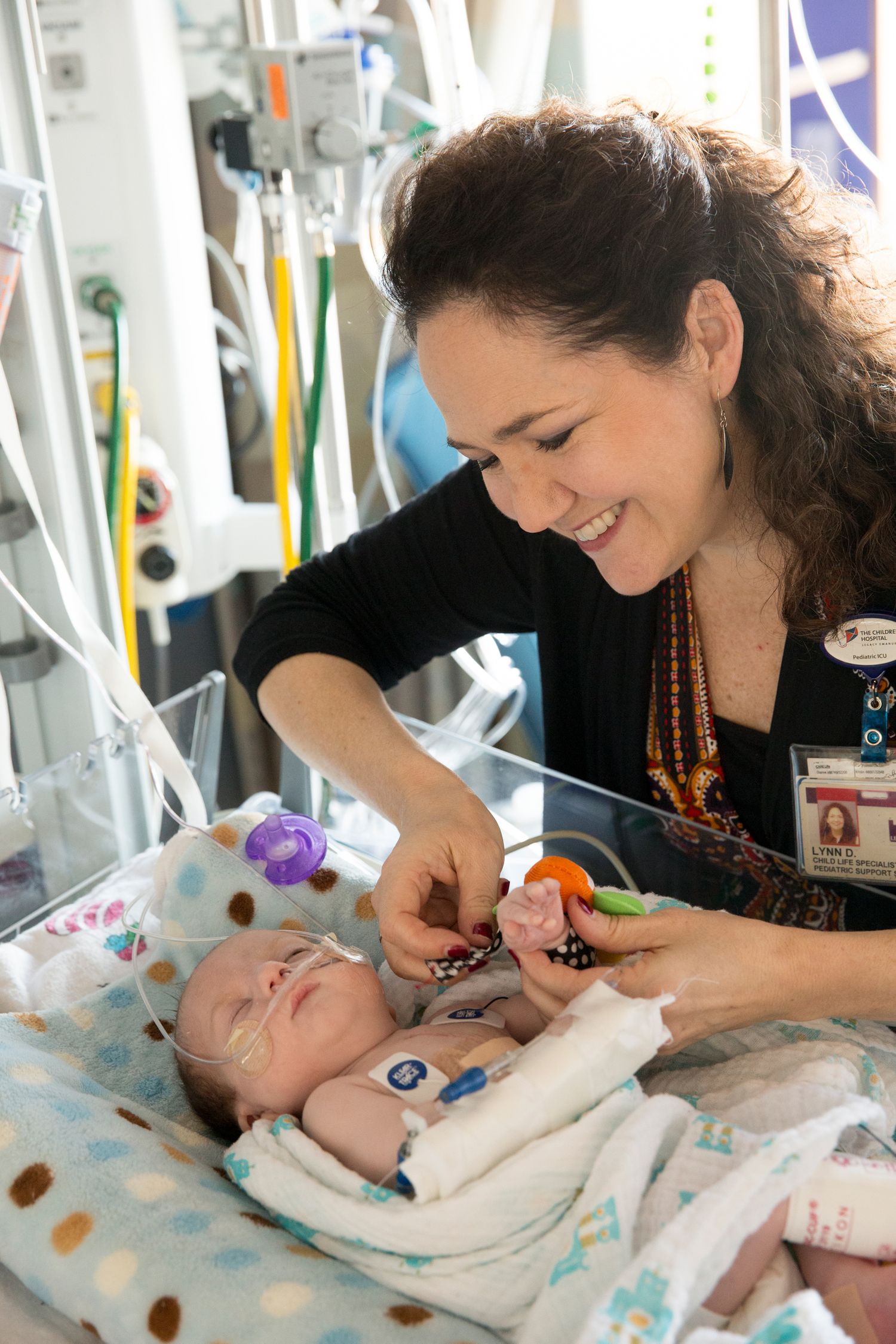 Healthcare provider attending to infant patient in hospital setting with medical equipment.