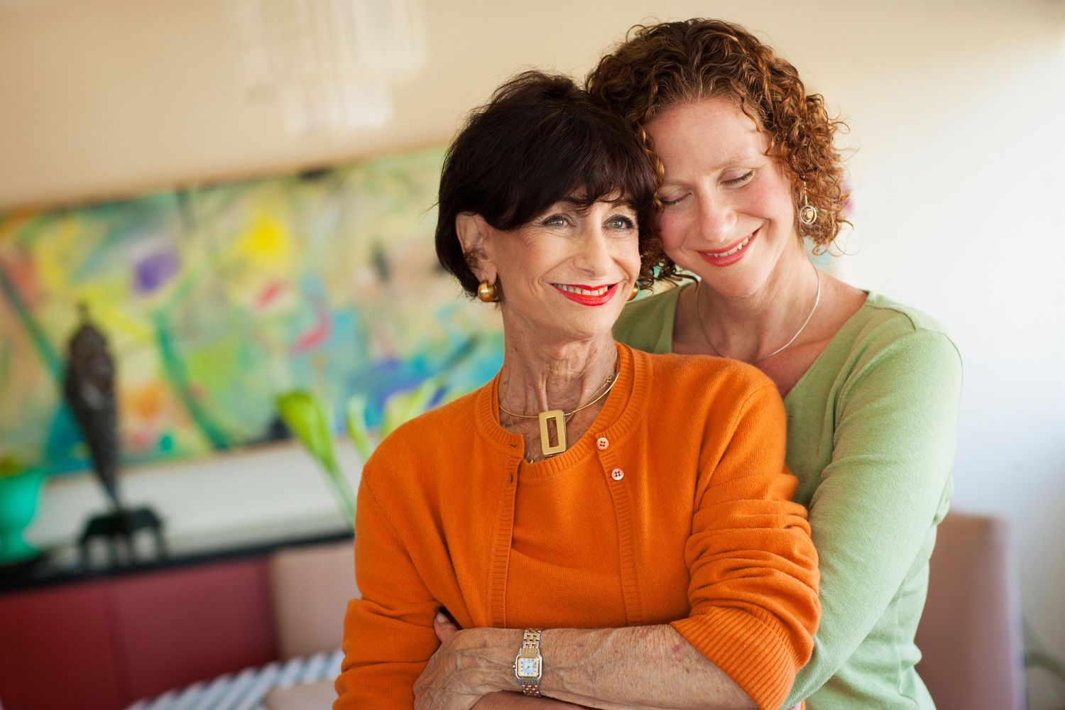 Two people sharing a warm embrace in front of colorful wall art.