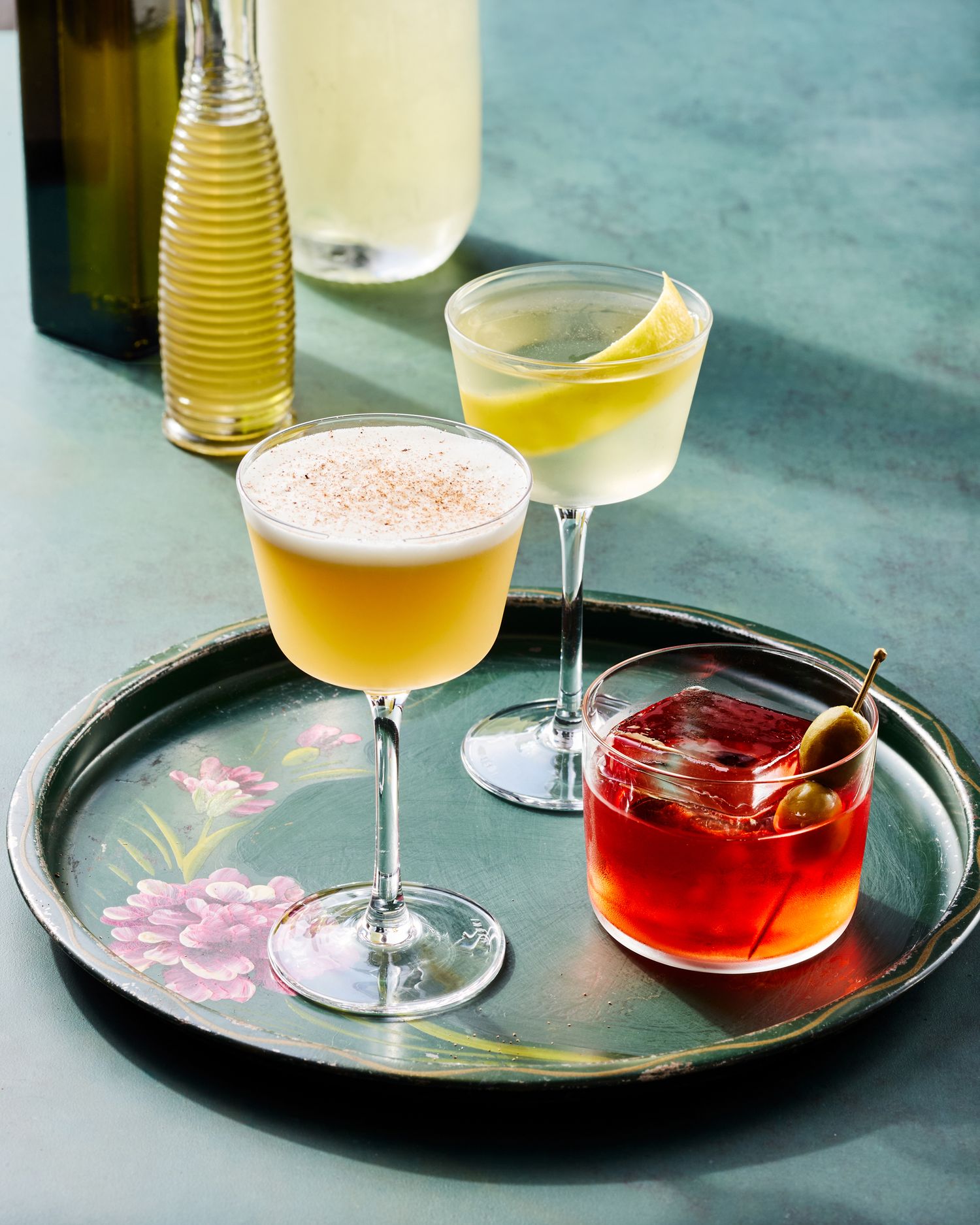 Colorful cocktails arranged on decorative serving trays with elegant glassware.