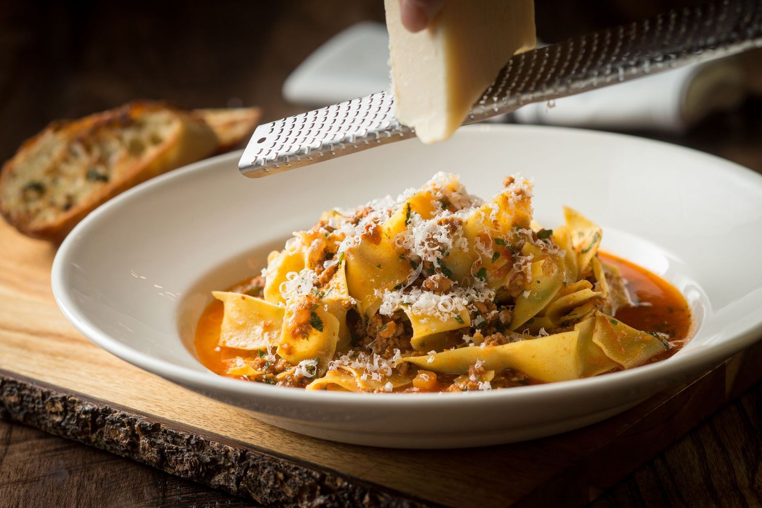 Pasta dishes with rich sauce plated on white dishes in warm lighting.