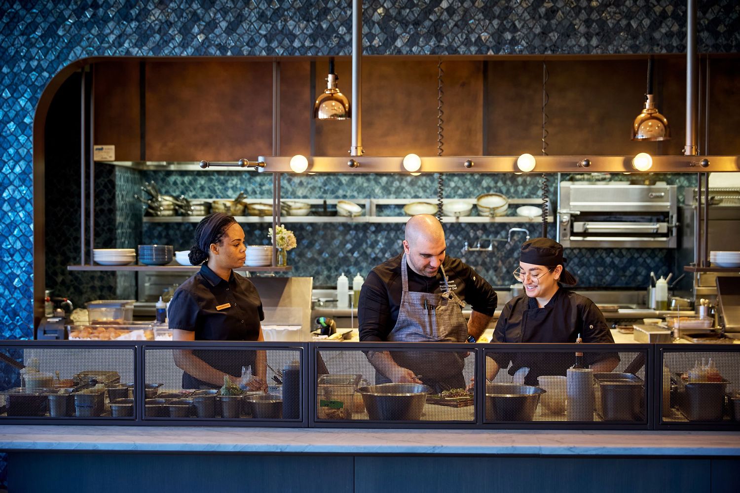 Modern restaurant bar interior with blue tile walls and industrial lighting.