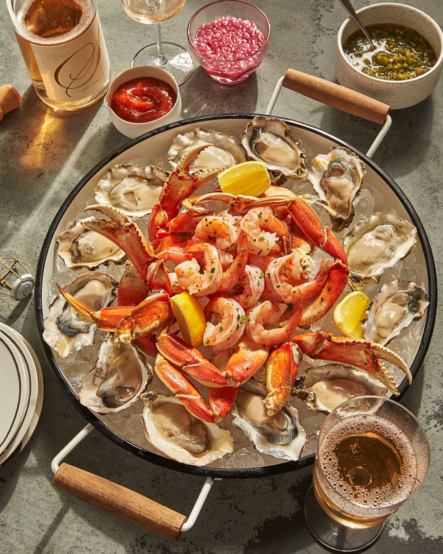 Fresh seafood platter with oysters, shrimp, and crab served with various sauces.