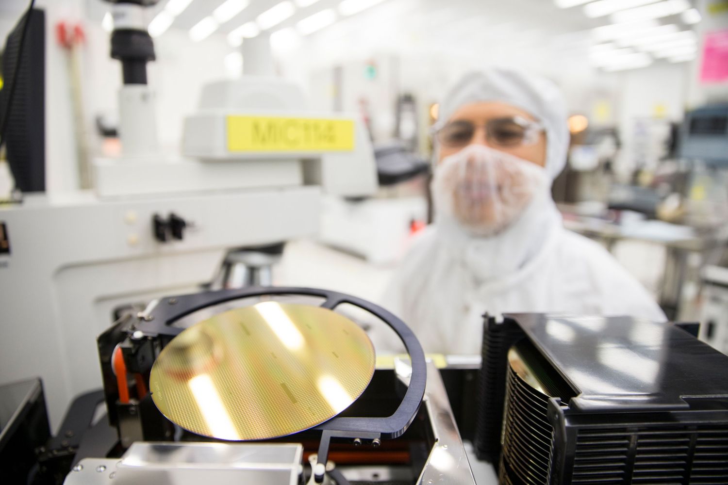 Scientists in clean room suits working with laboratory equipment and samples.
