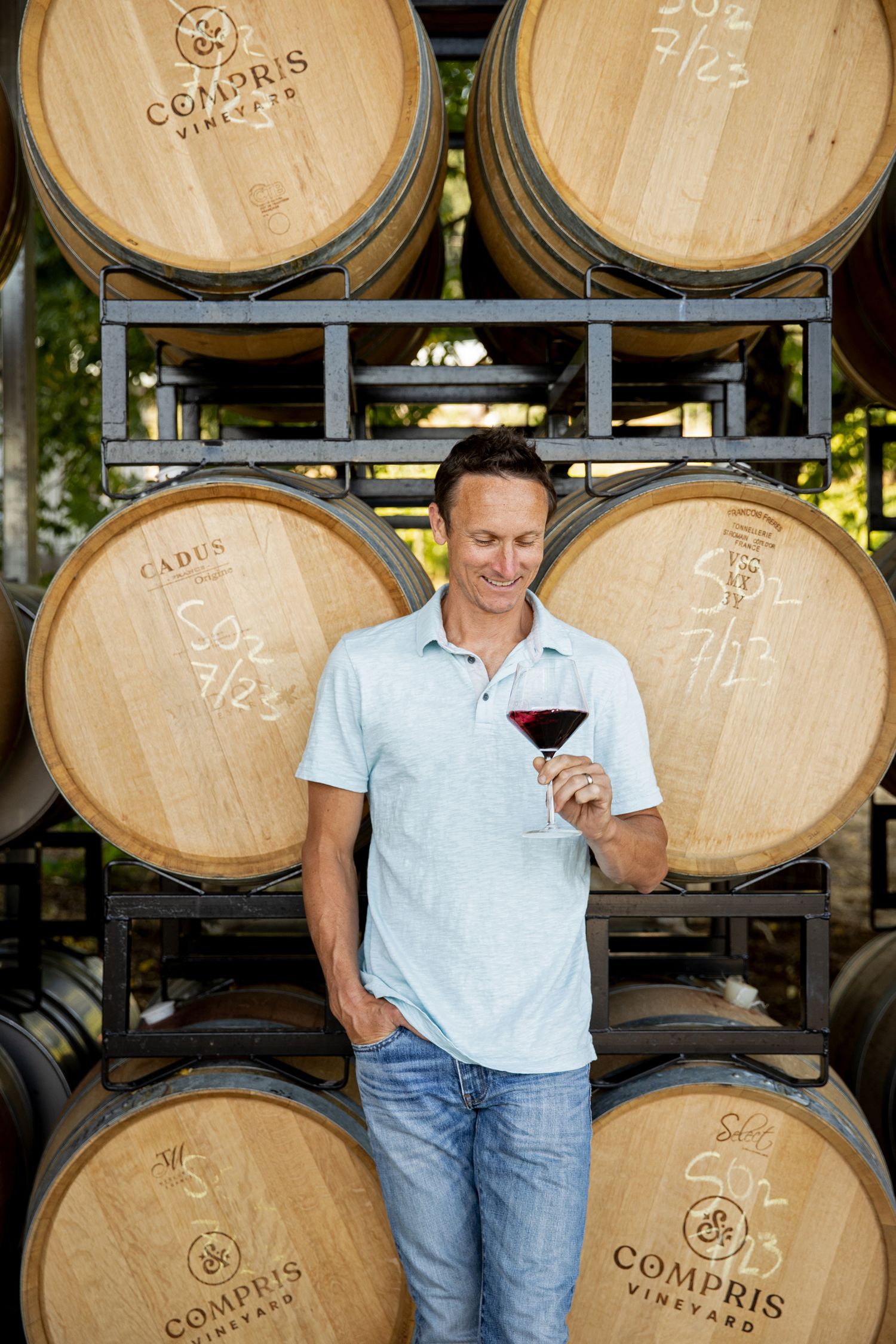 Wine tasting setup with oak barrels stacked in cellar background.