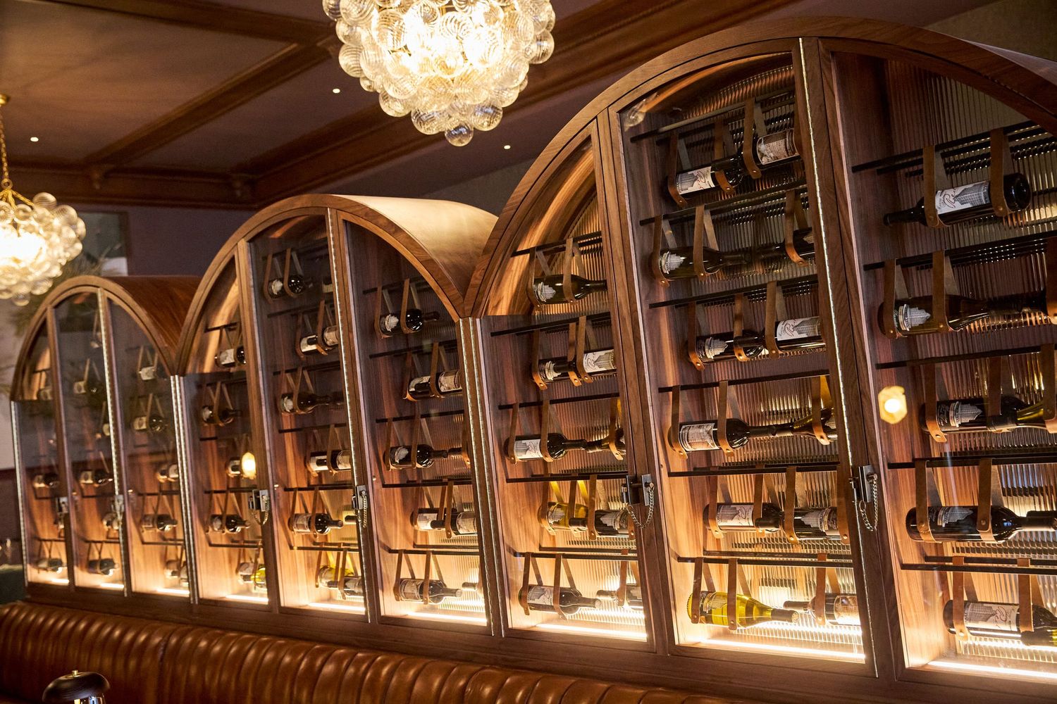 Curved wooden ceiling beams and wine bottle displays in an elegant restaurant interior.