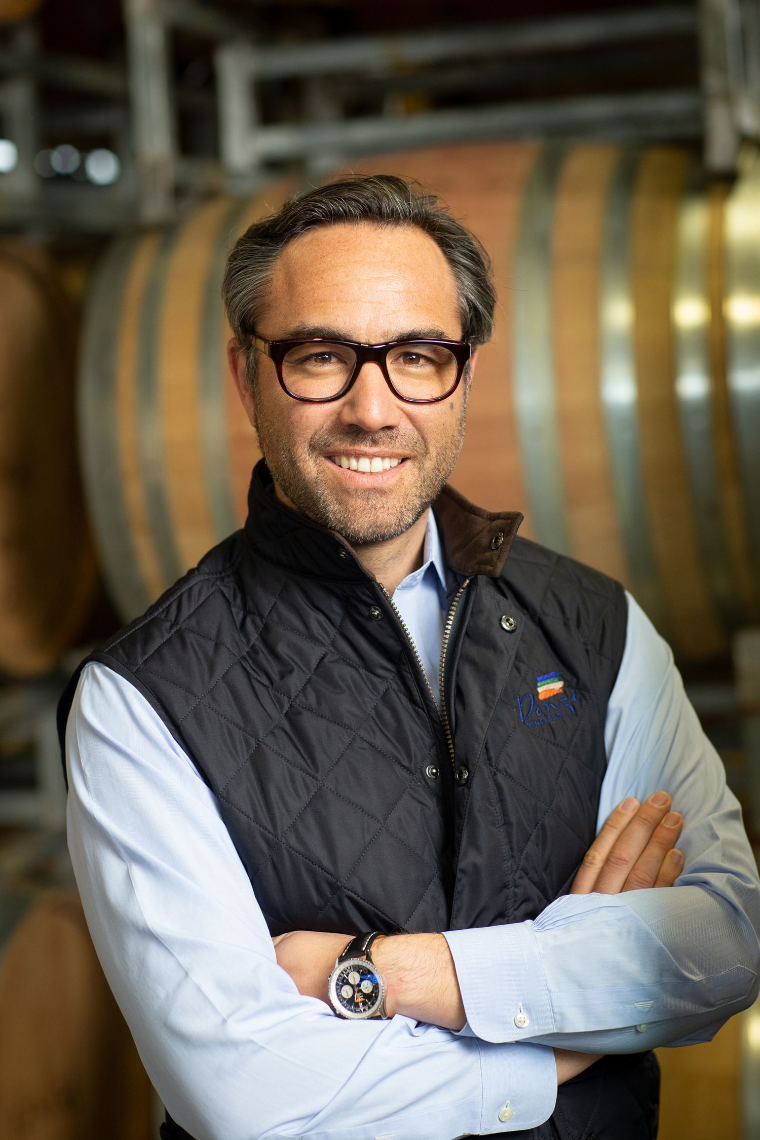 Professional winemaker standing in barrel room wearing business casual attire.
