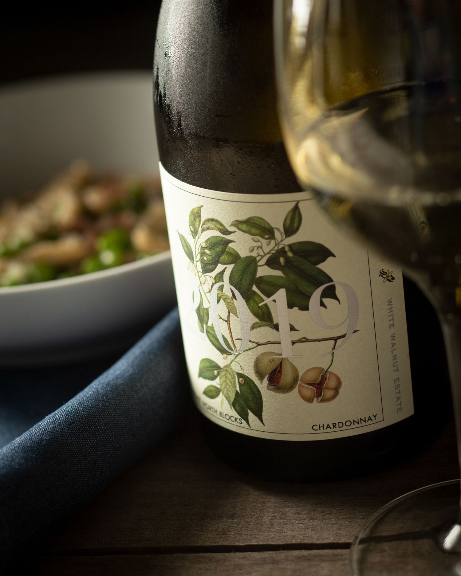 Wine bottle with botanical label design photographed on dark surface.