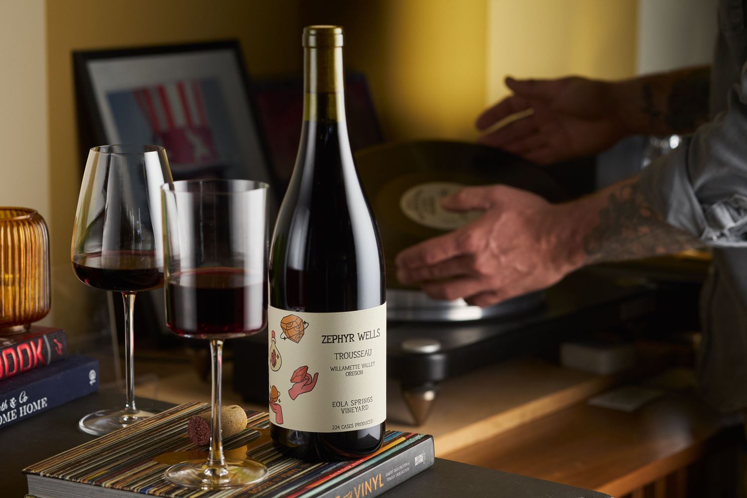 Wine bottle and glasses displayed on dark table with ambient lighting.