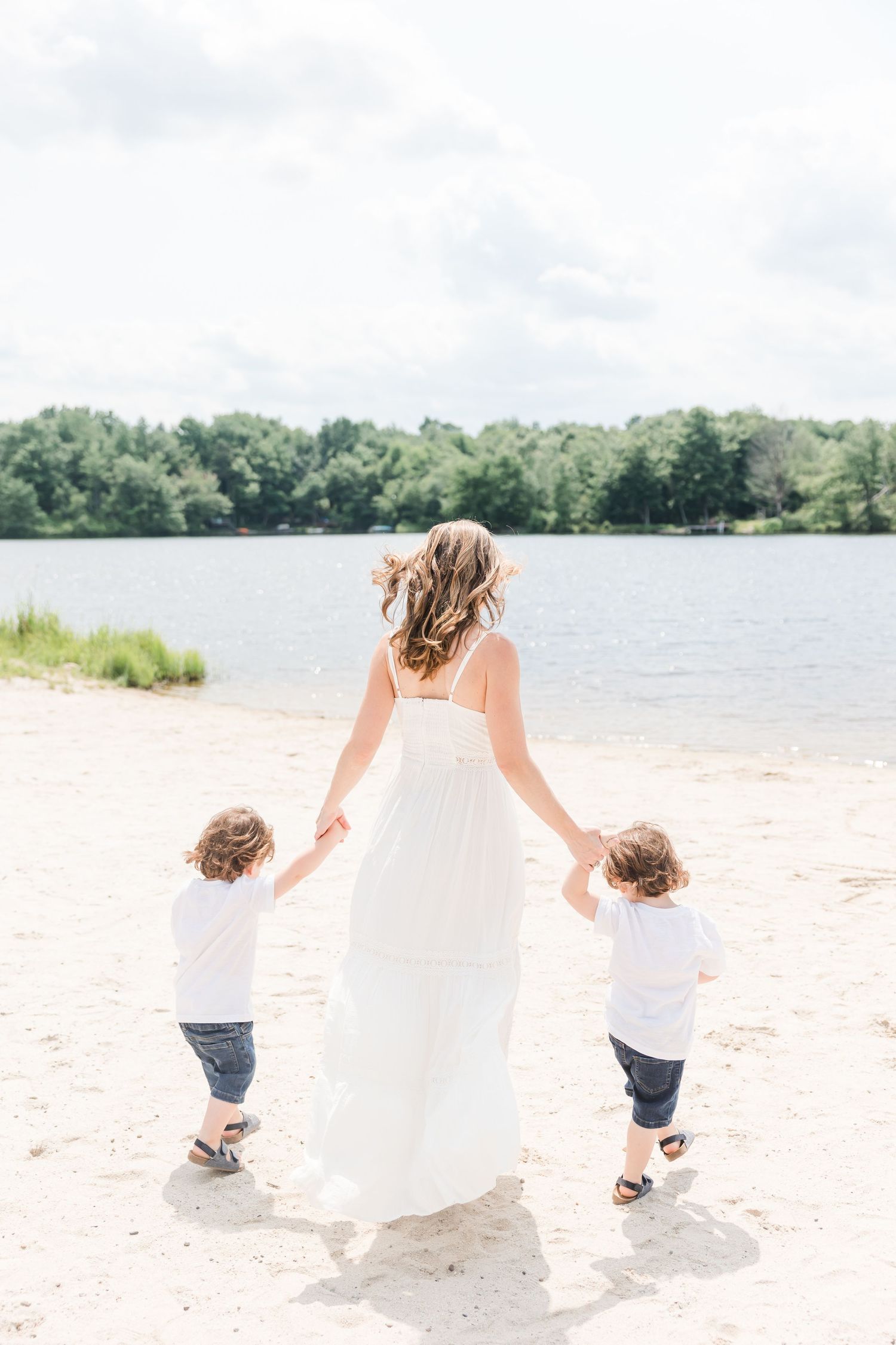 Serene lakeside scene with sandy beach and tree-lined shore on a bright summer day.