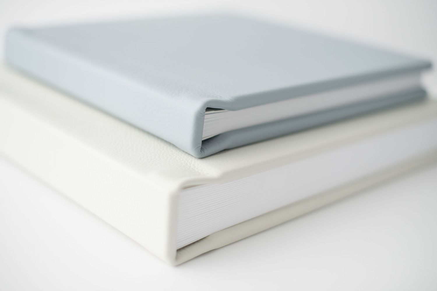 Two minimal white and light blue bound photo albums stacked together.