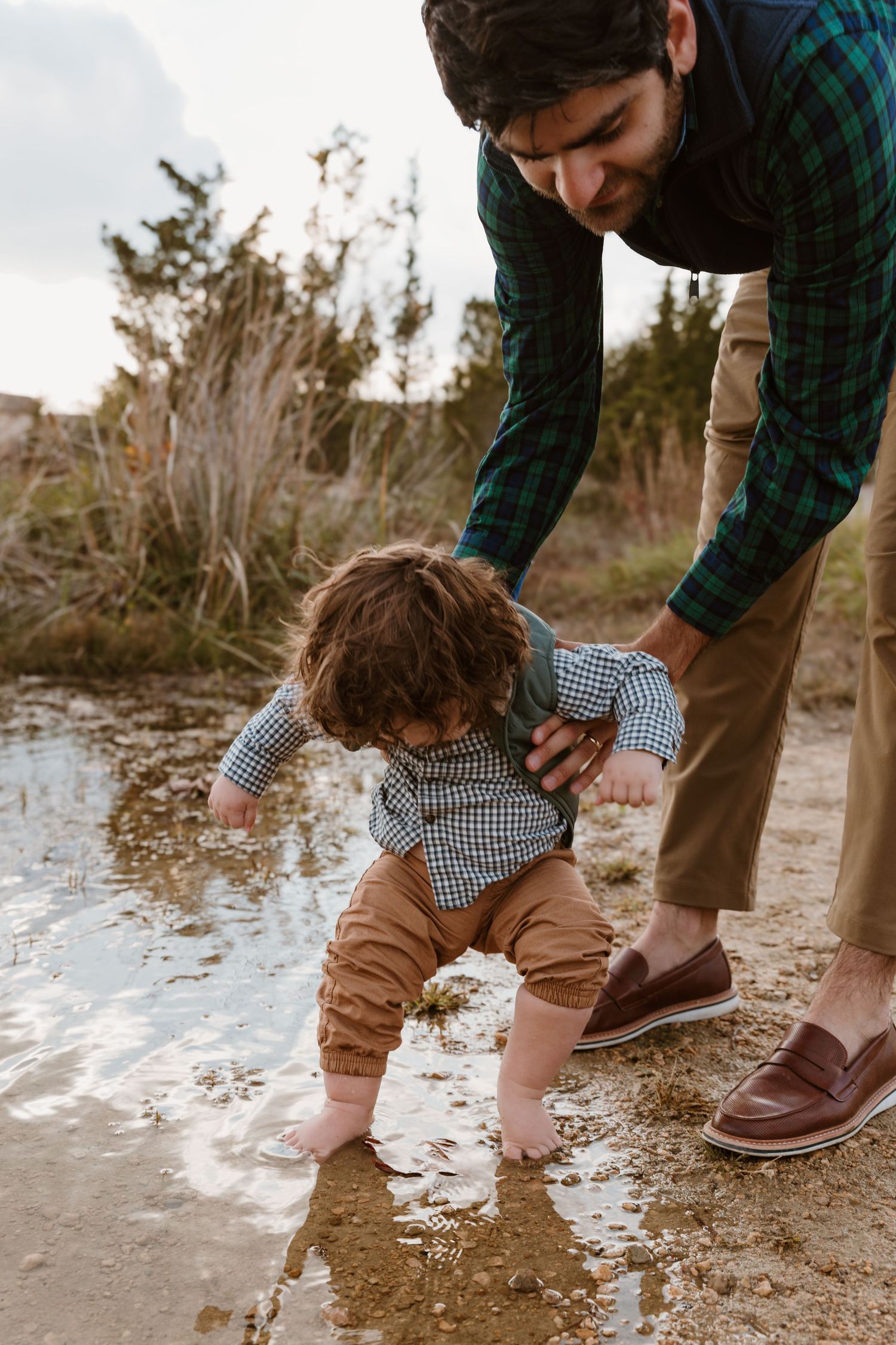 Fathers lowers sons toes into water during a family session at Oakes Quarry in Fairborn, OH. Photographed by Vicci Photo of Dayton, OH