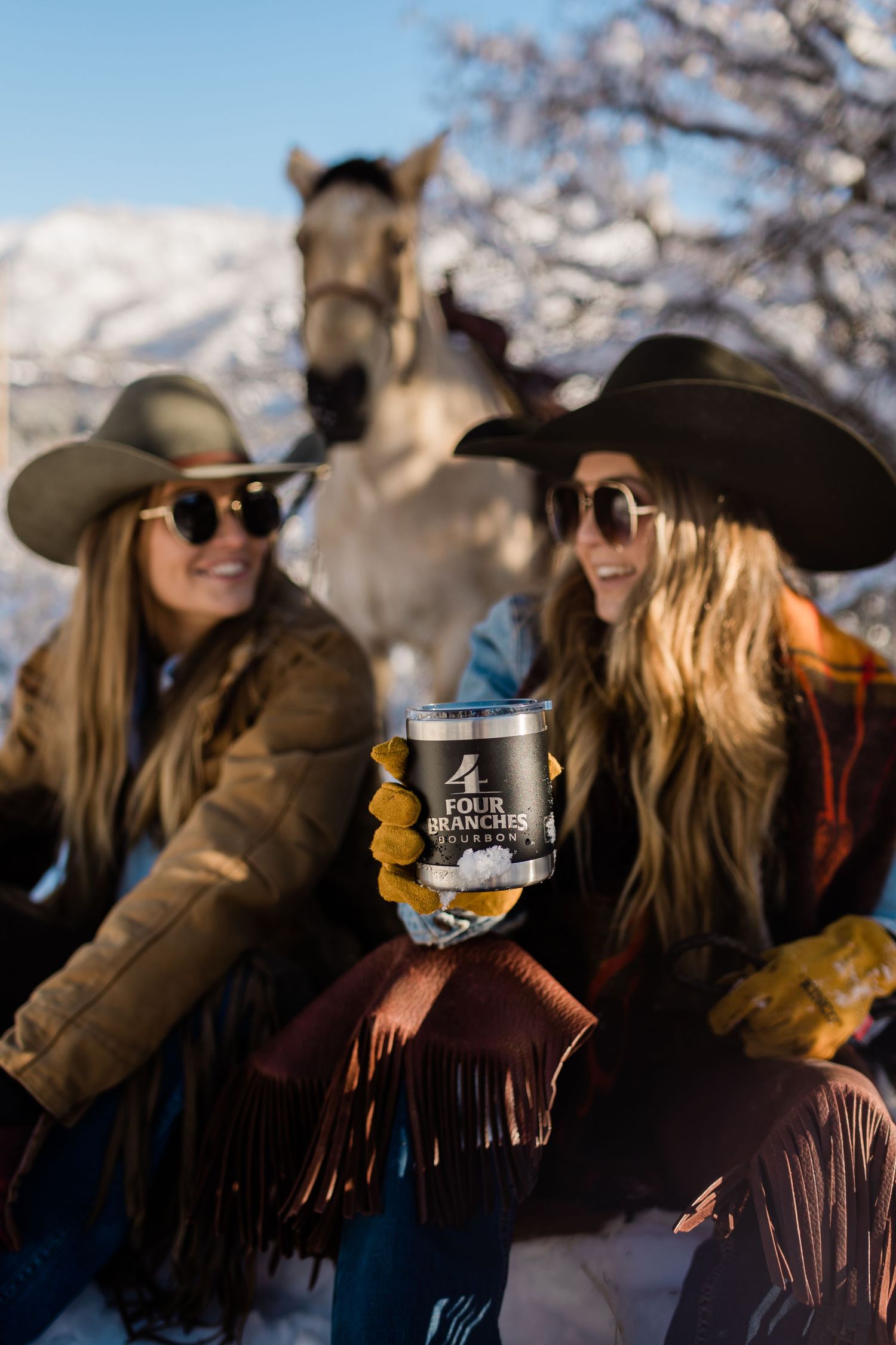 Western-styled gathering with horses and drinks in a snowy mountain setting.