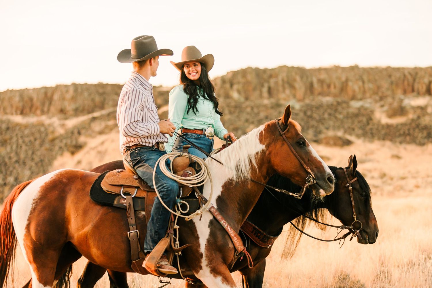 Riders on horseback traverse a scenic desert landscape during a guided trail ride at sunset.