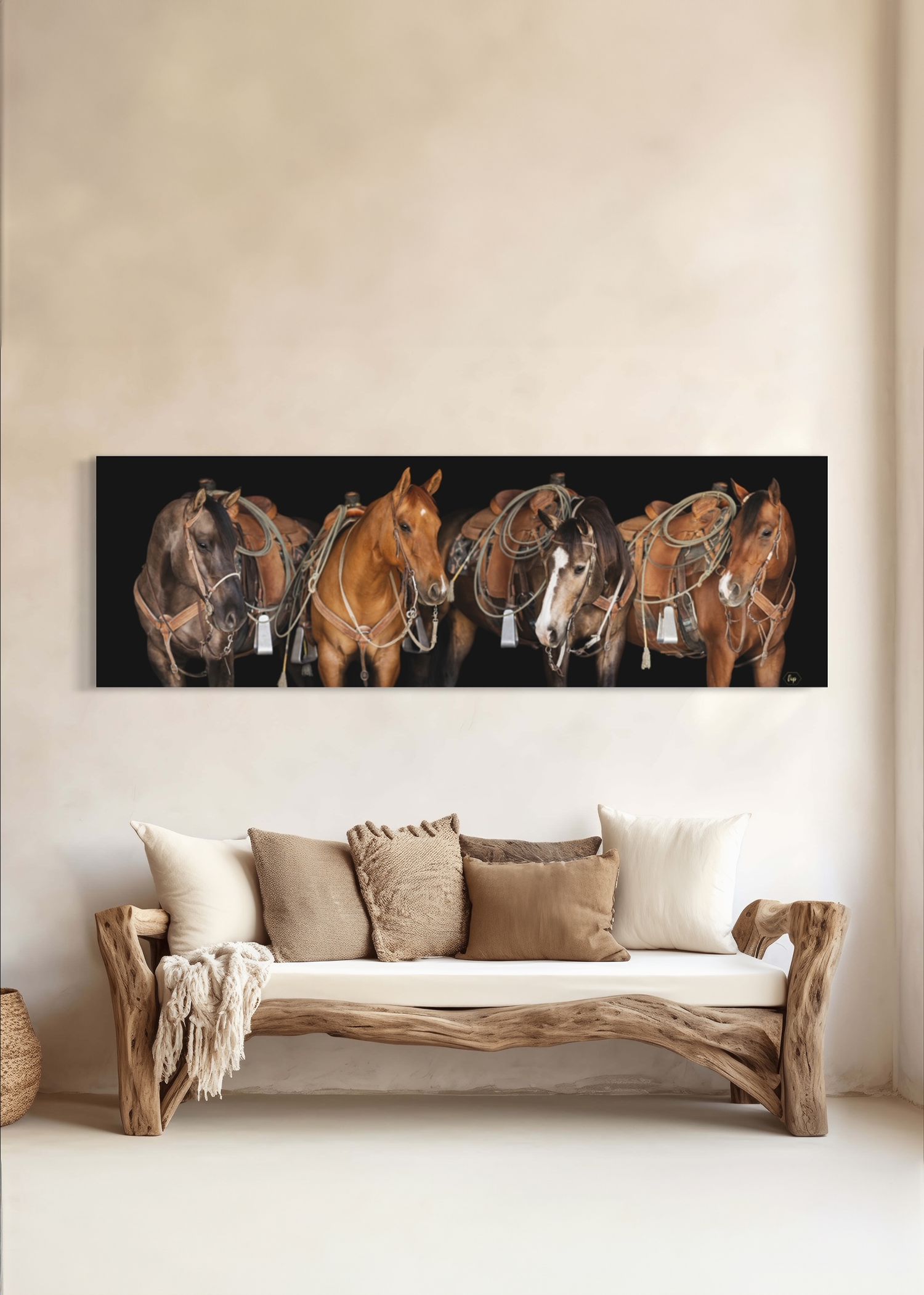 Beautiful horizontal art piece featuring four horses in brown tones hanging above a rustic wooden couch with neutral pillows.